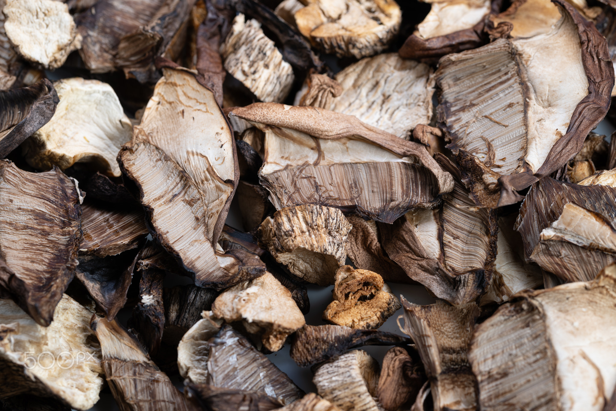 Gourmet dried mushrooms for pantry use, sliced caps and stems arranged in warm tones, conveying umam