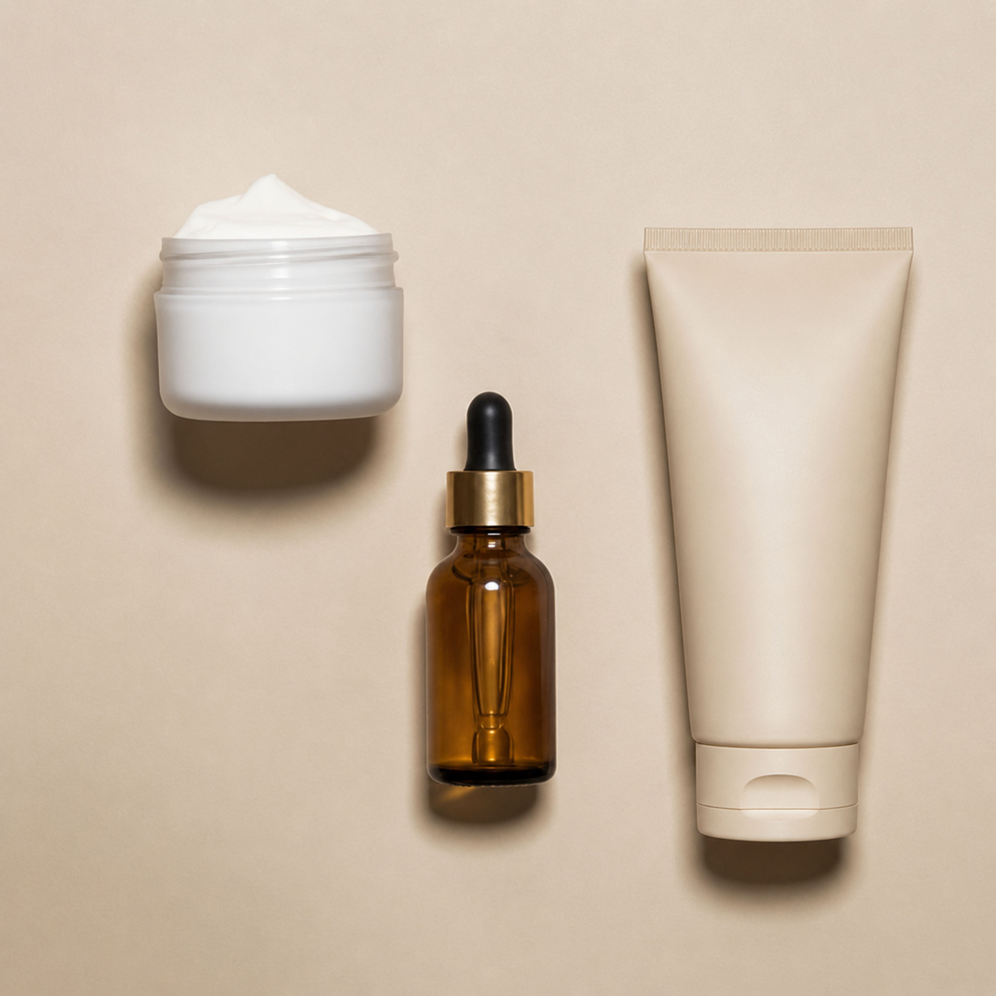 Luxury Minimal Skincare Flat Lay with Amber Serum Bottle and Cream Jar.