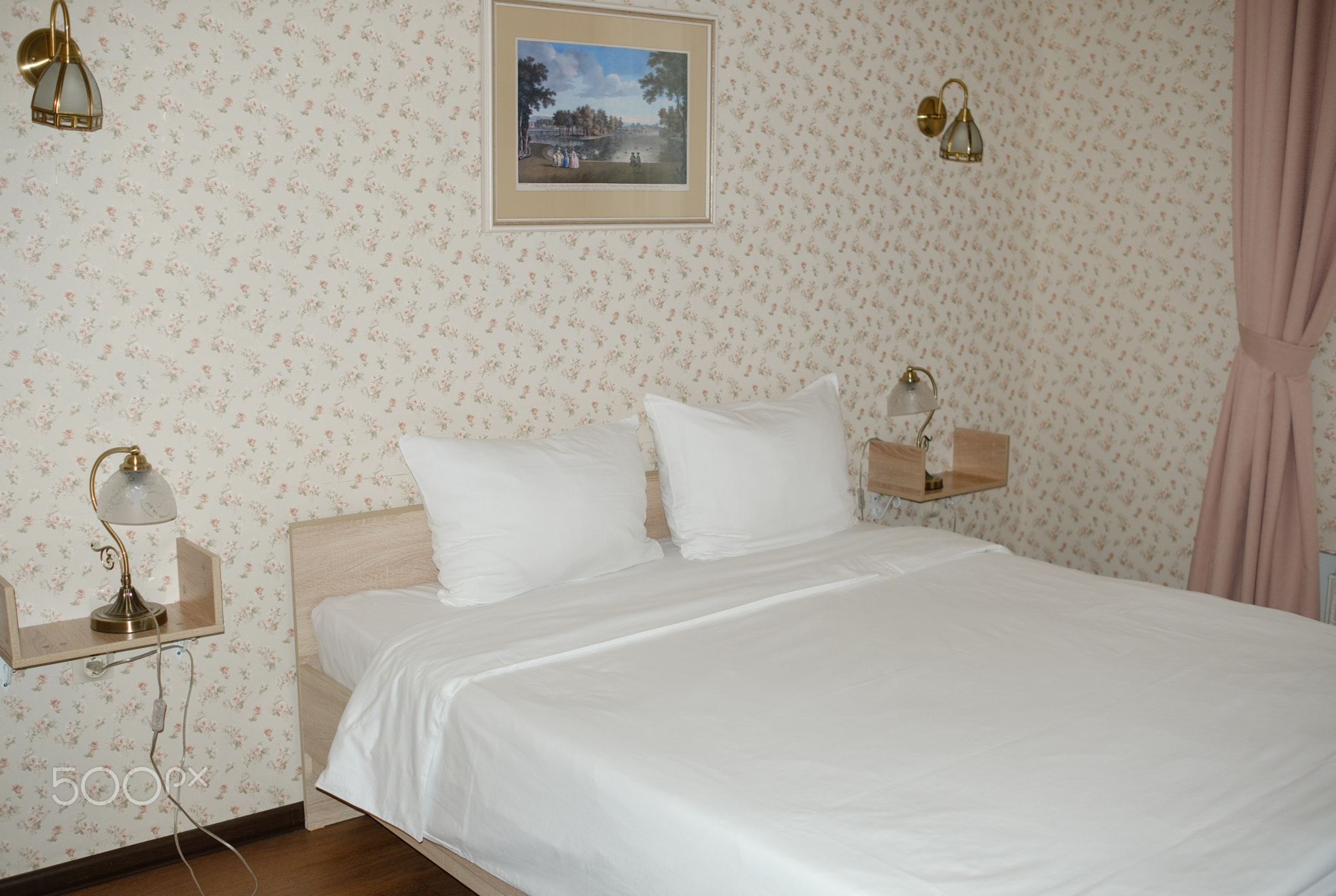 Modern bedroom interior with a double bed, decorative wall art, and bedside lamps in a cozy floral