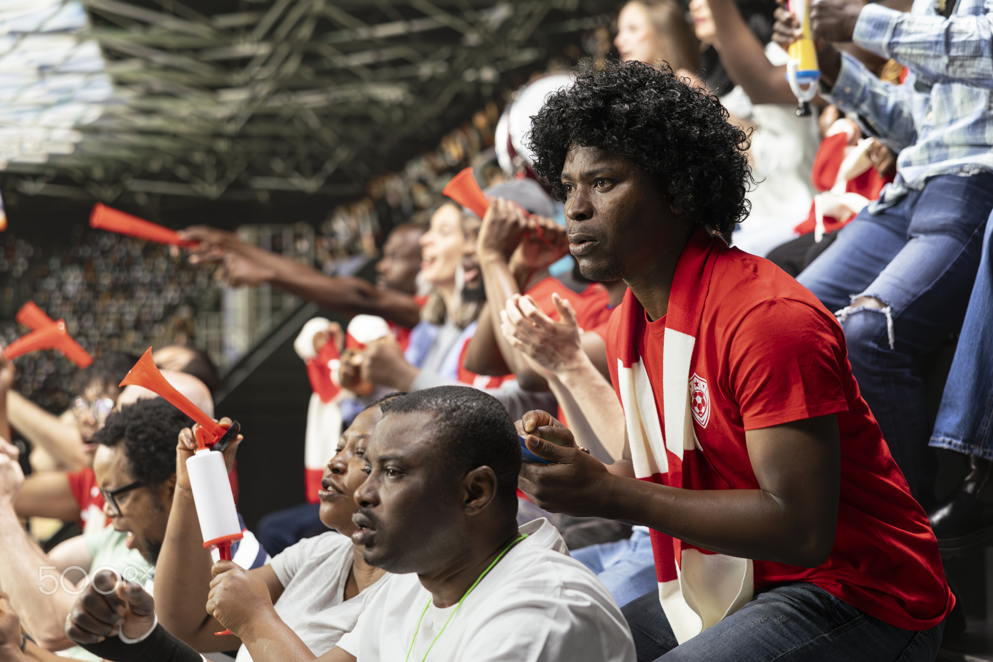 Serious football supporter watching tense match moment from stadium stands