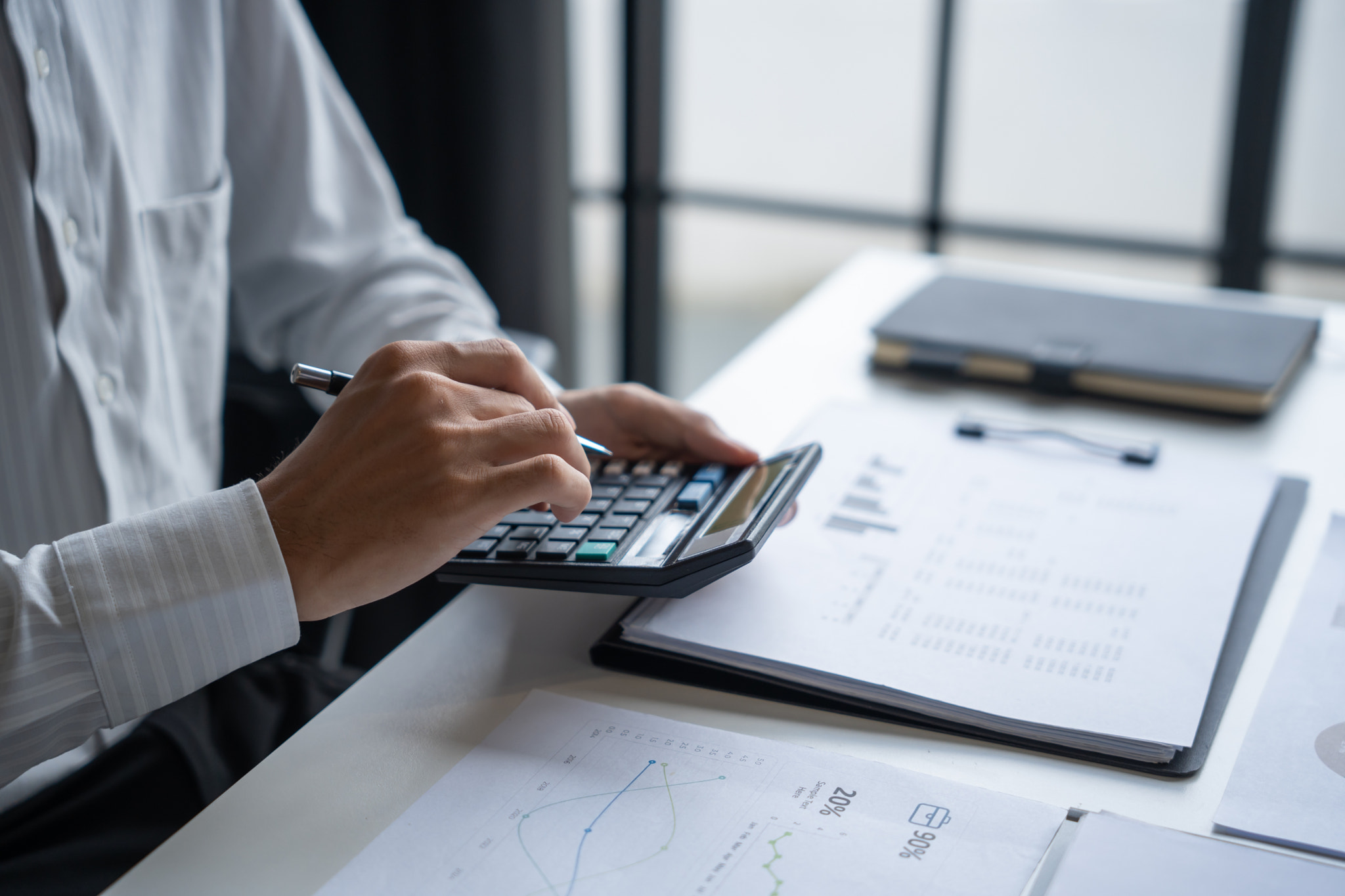 #V Midsection of businessman using calculator at desk in office