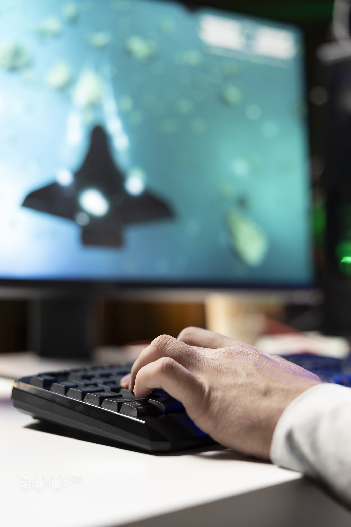 Man using gaming keyboard to fly spaceship in SF videogame, close up