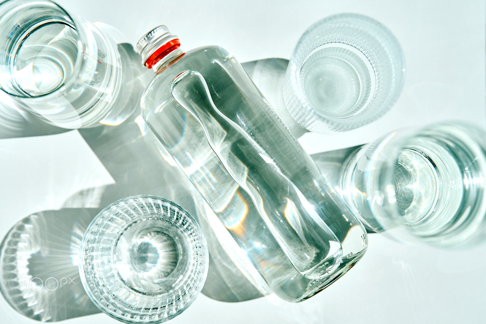 Glass bottle with water and empty glasses