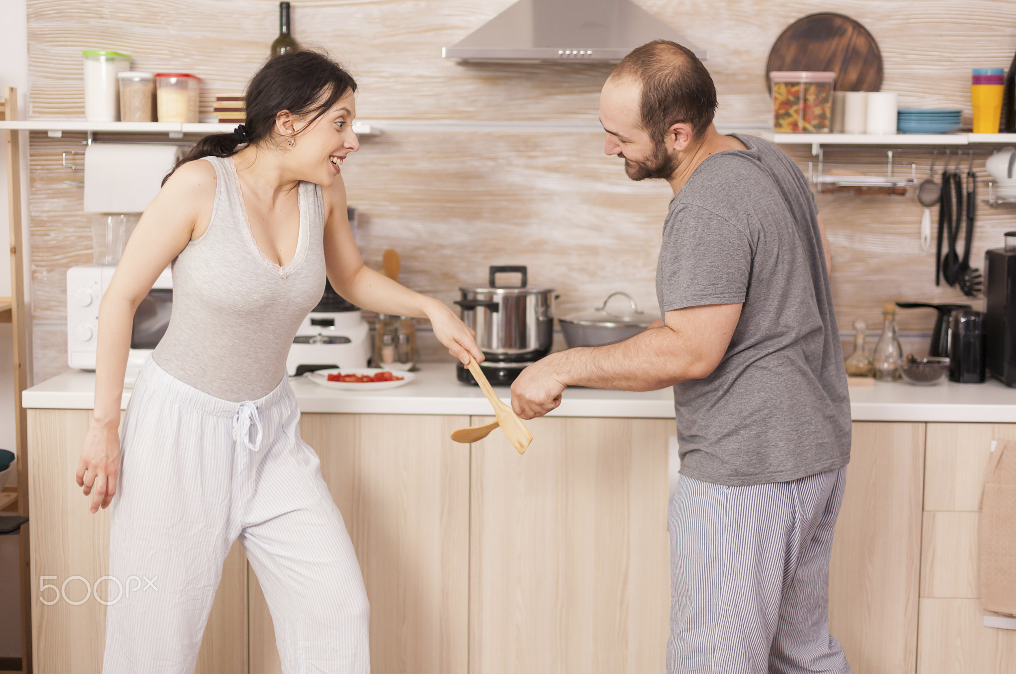 Couple play with kitchen spoons