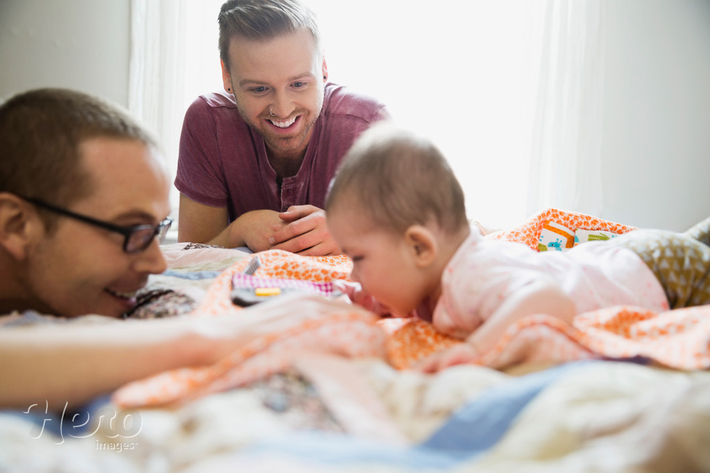 Homosexual couple playing with baby on bed by Hero Images Hero Images on 500px.com