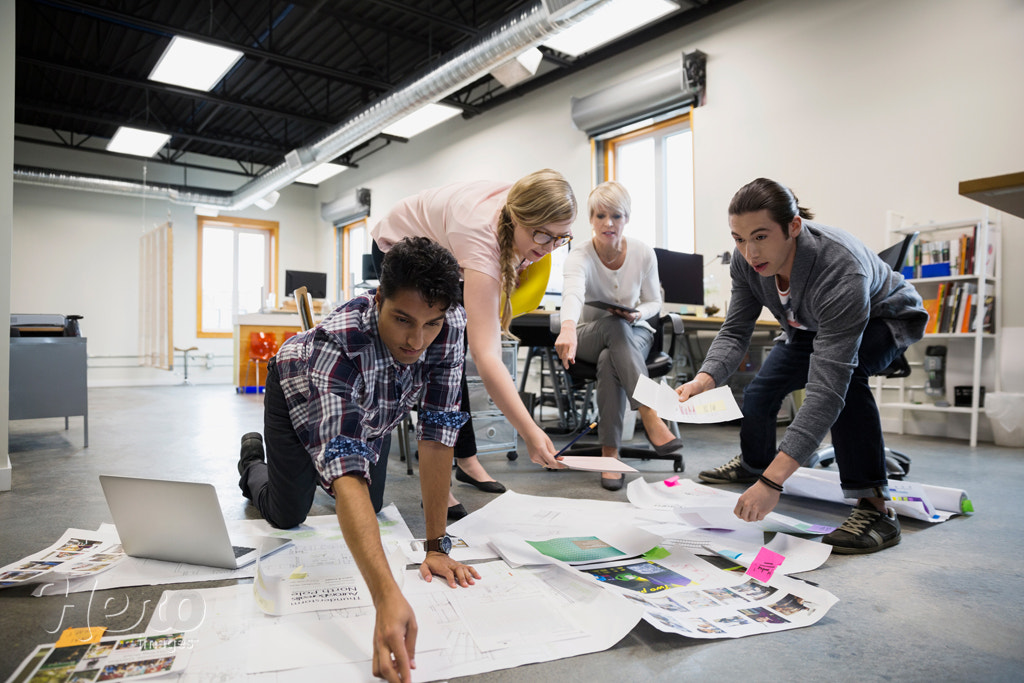 Graphic designers meeting reviewing proofs on office floor