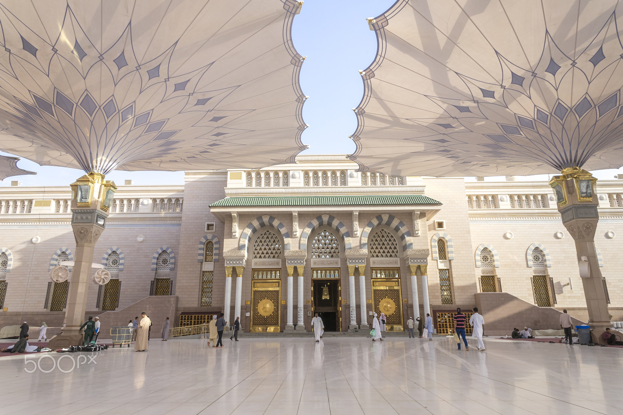 MEDINA - MARCH 06 : Pilgrims walk underneath giant umbrellas at Nabawi Mosque compound on March 06,