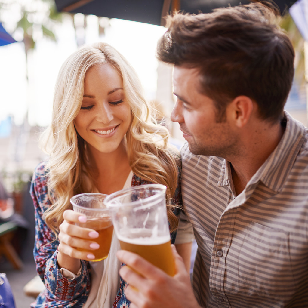 romantic couple drinking beer in outdoor pub or bar making a toast by Joshua Resnick on 500px.com