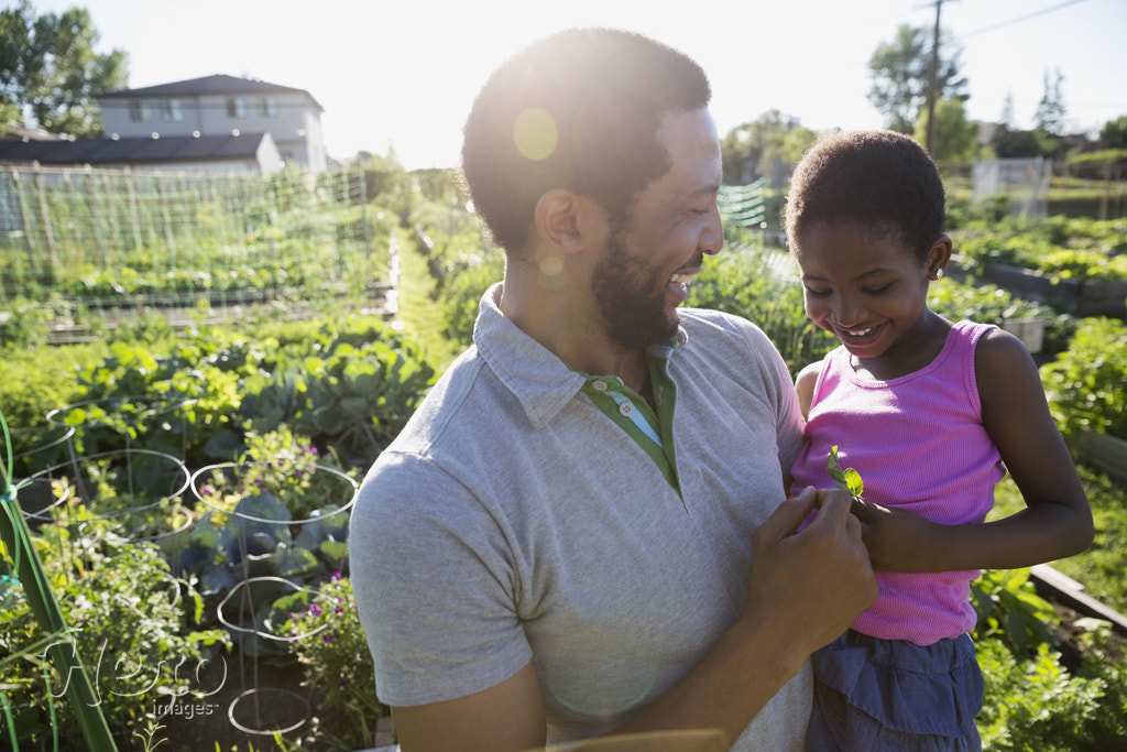 Father holding daughter in sunny garden