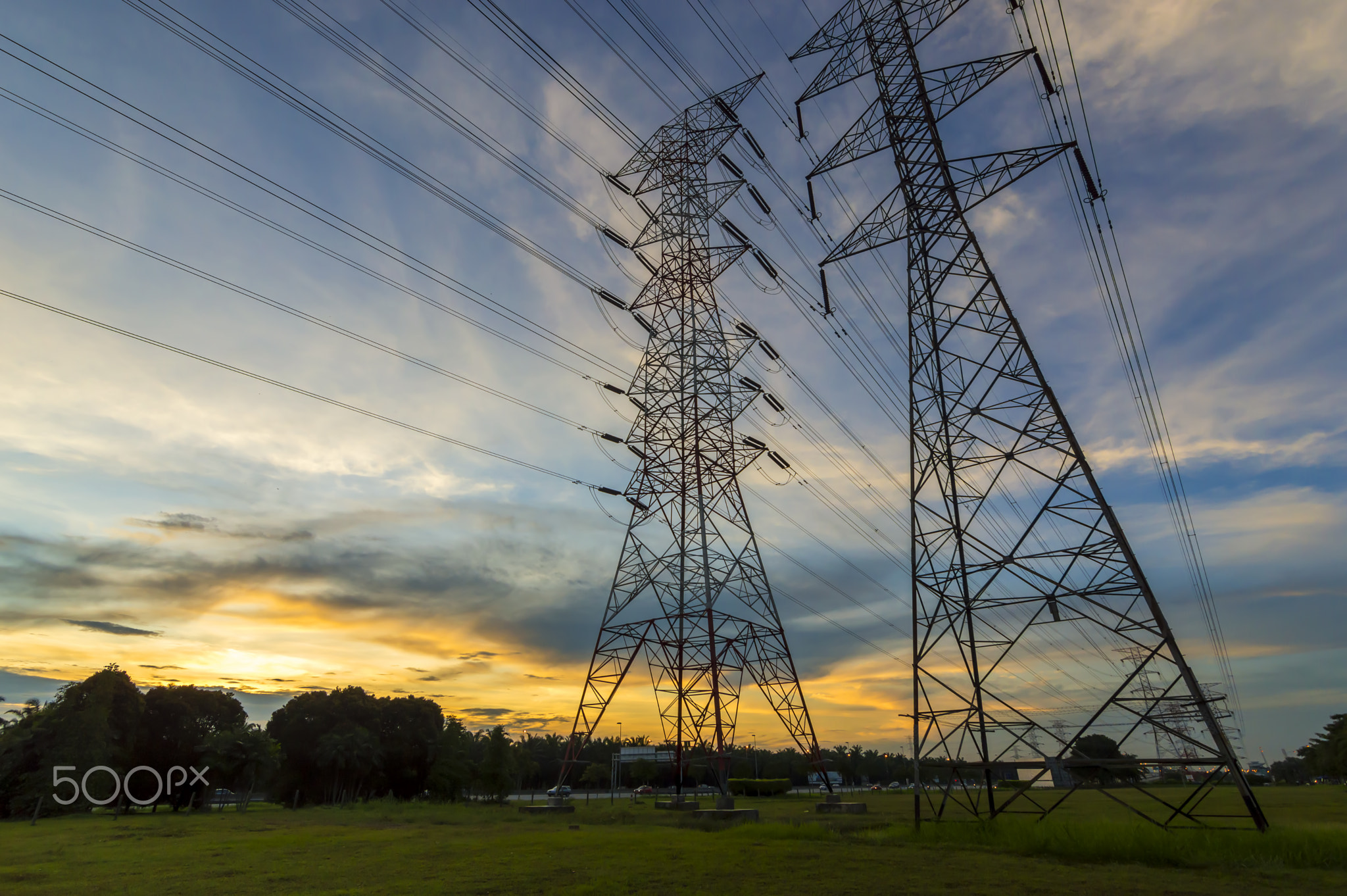 High-voltage power transmission towers in sunset sky background