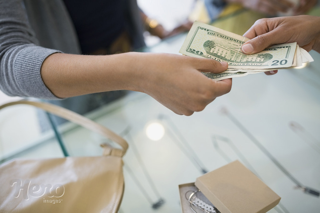 Woman paying cash at shop counter by Hero Images Hero Images on 500px.com