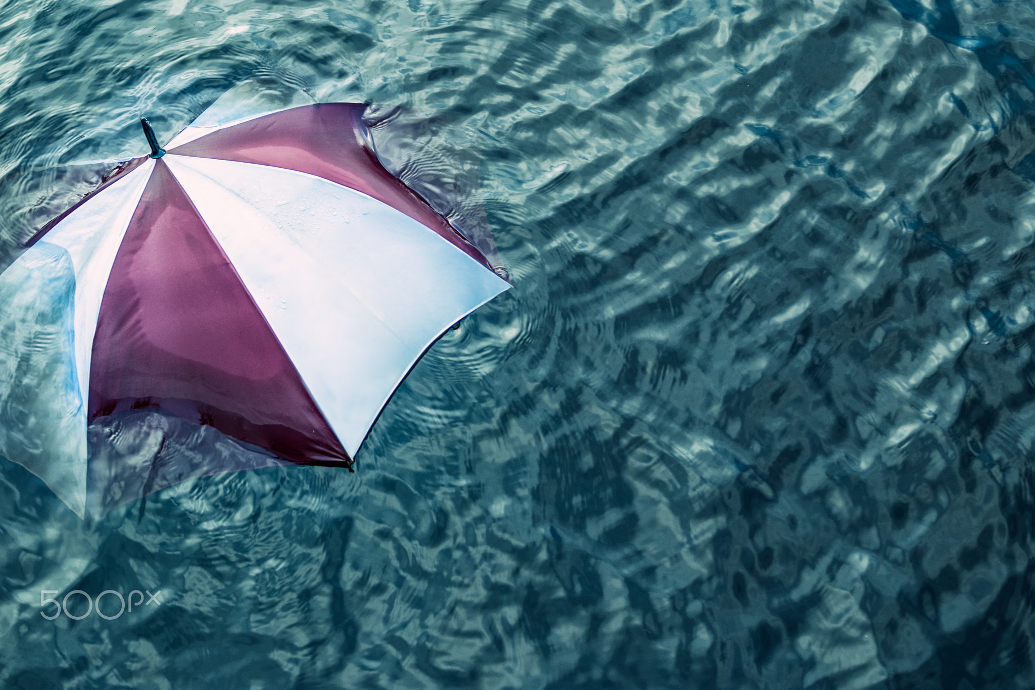 Raining too much ... Escape the bad weather, vacation concept. Umbrella swimming in water.