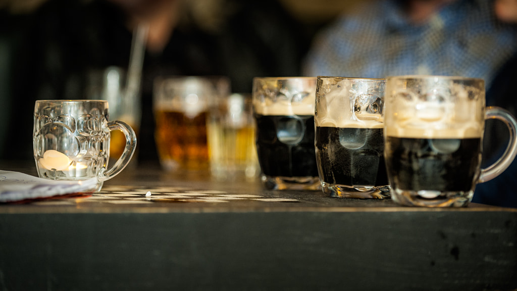 Horizontal colour image of half full beer glasses on the table of a bar by Andrea Obzerova on 500px.com