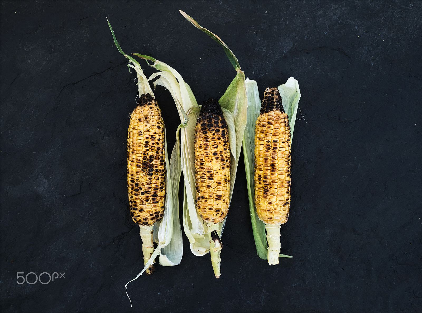 Nikon D610 + ZEISS Distagon T* 35mm F2 sample photo. Grilled corn over black slate stone background, top view. photography