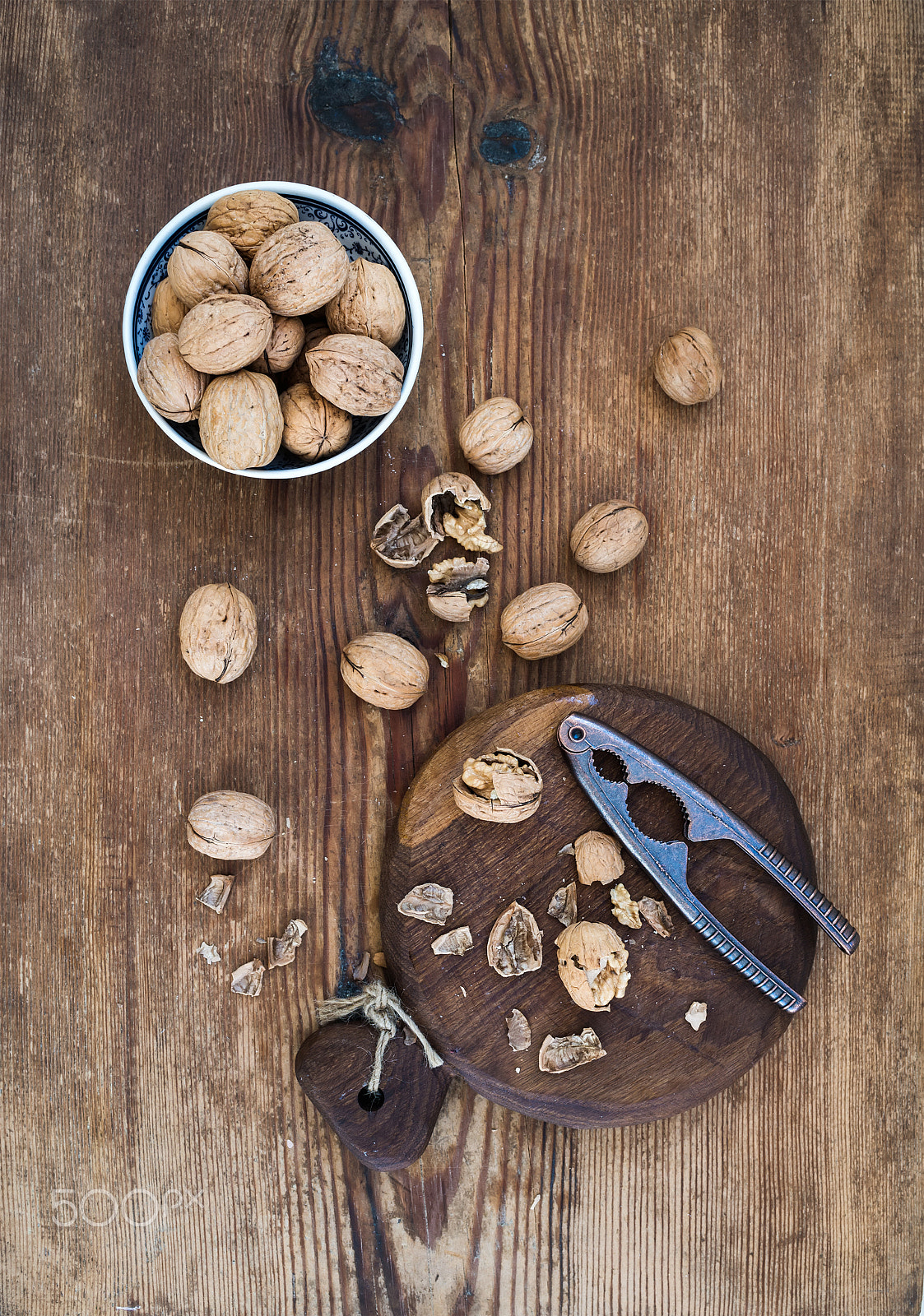 Nikon D610 + ZEISS Distagon T* 35mm F2 sample photo. Walnuts in ceramic bowl and on cutting board with nutcracker over  rustic wooden background, top vie photography