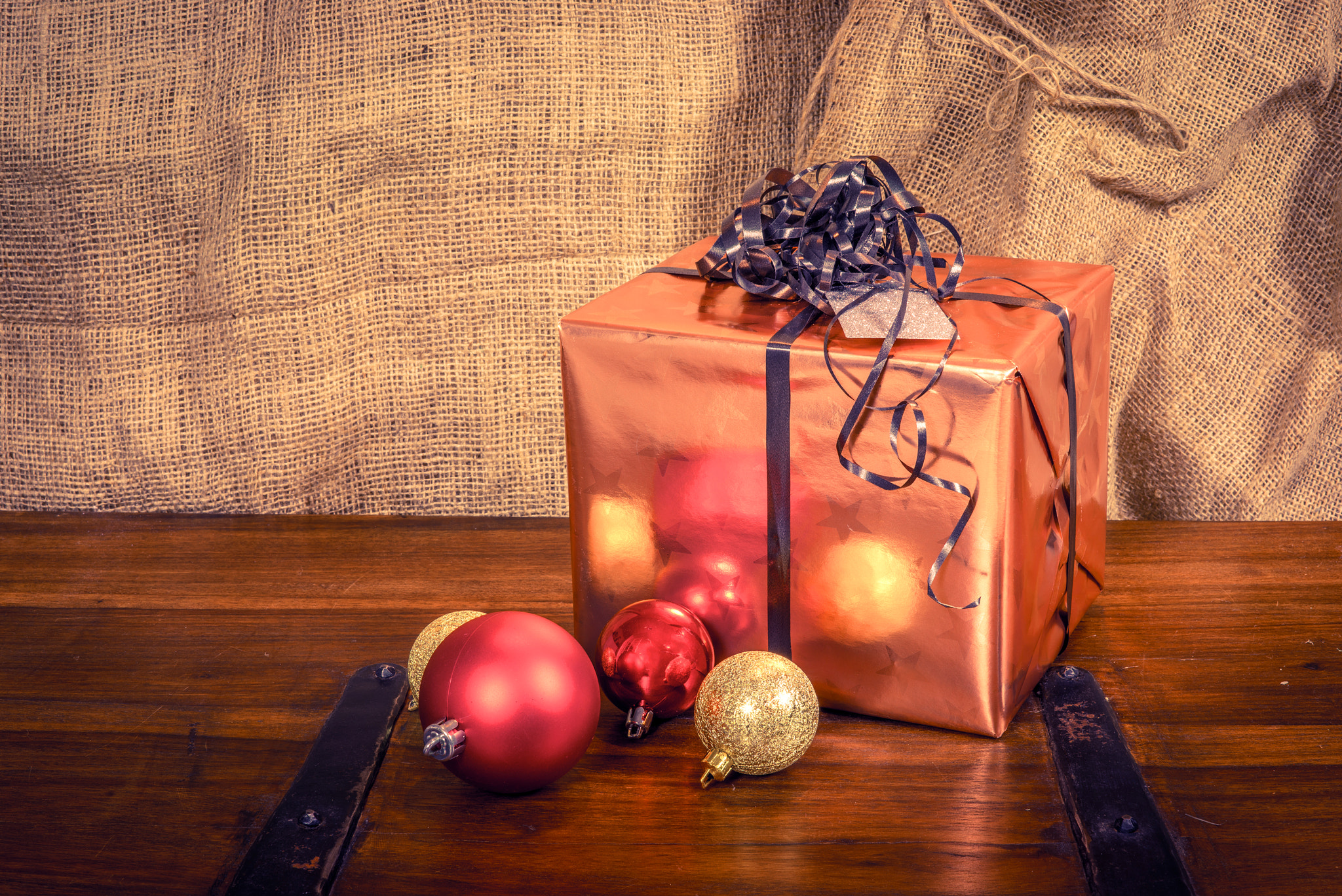 Sony a7R + Sony 50mm F1.4 sample photo. Shiny christmas gift on a wooden table photography