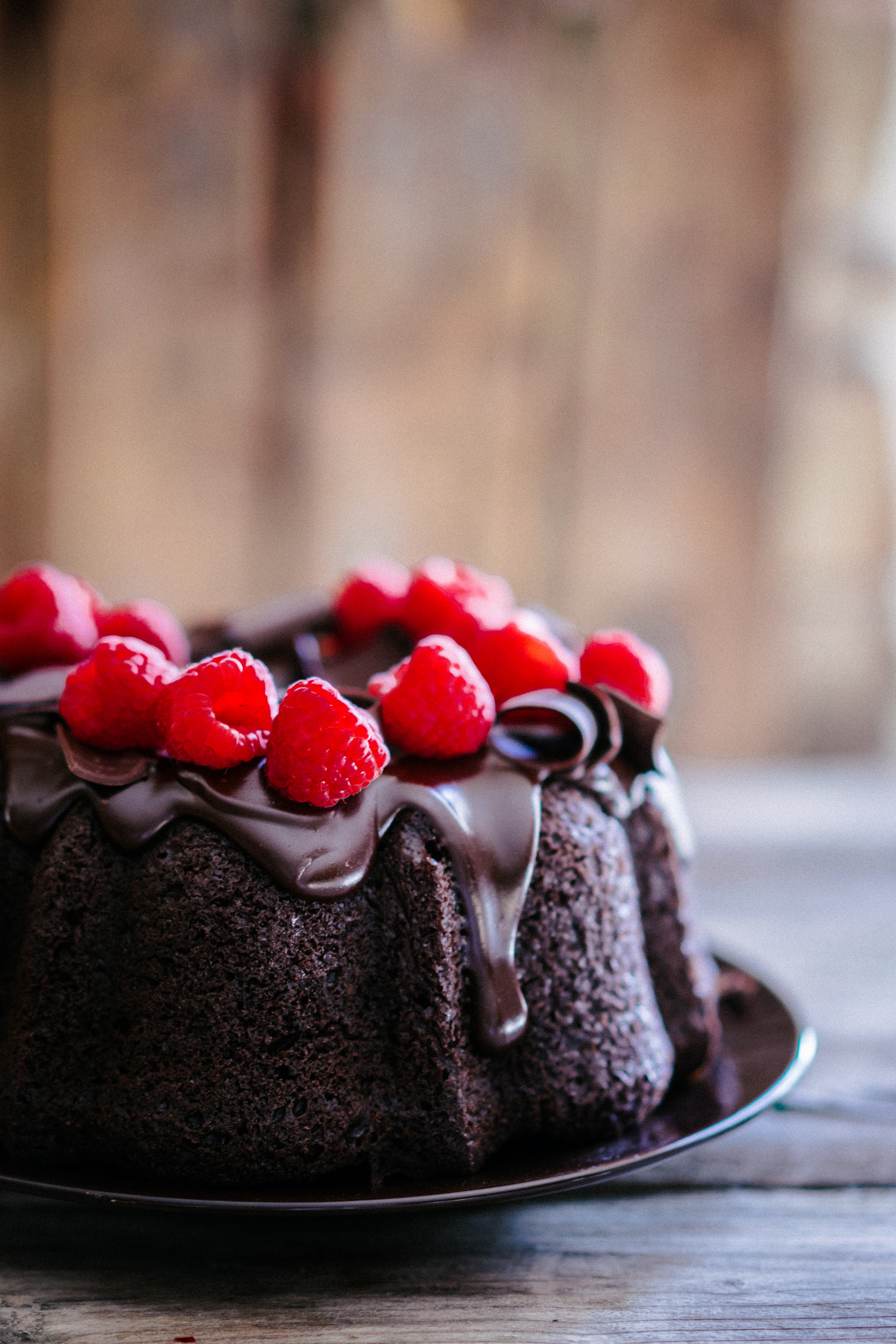 Chocolate cake with raspberries on rustic wooden background