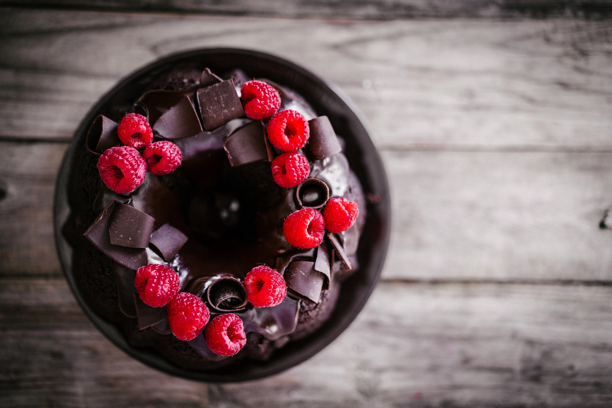 Chocolate cake with raspberries on rustic wooden background