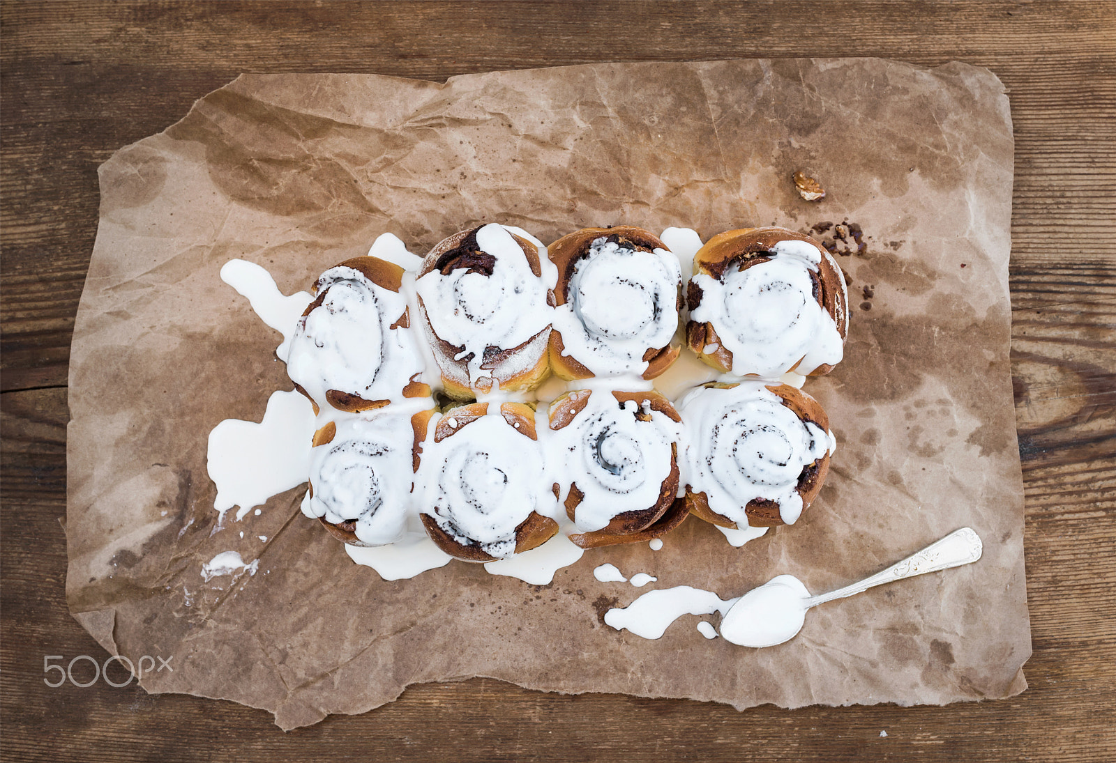 Nikon D610 + ZEISS Distagon T* 35mm F2 sample photo. Cinnamon rolls with cream cheese icing on piece of oily craft paper over rustic wooden background photography