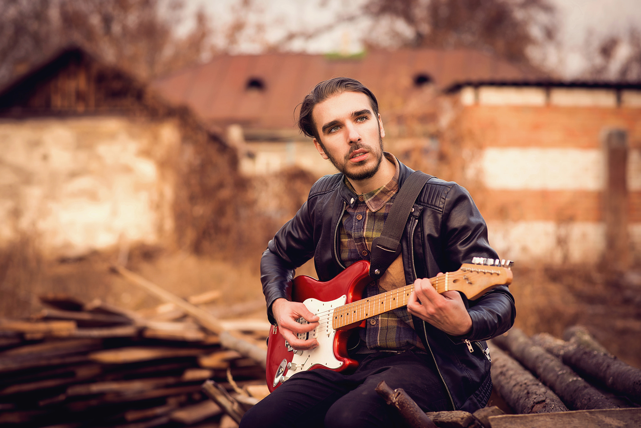 Young man playing guitar in countryside. Outdoors portrait