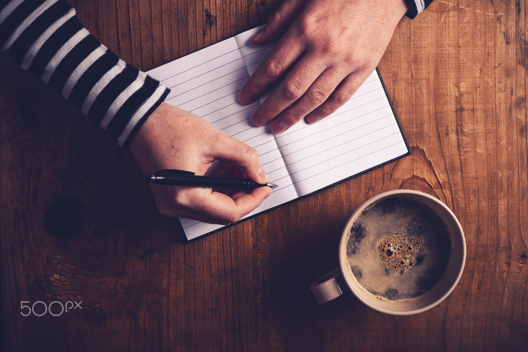 Woman drinking coffee and writing a diary note