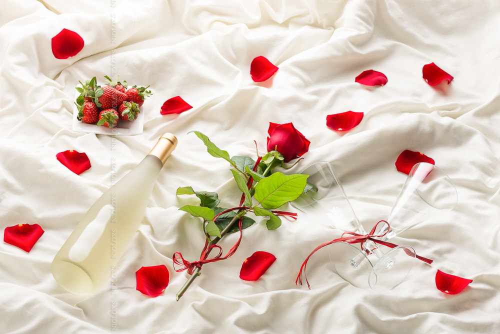 Rose, wine,  petals and strawberry on bed