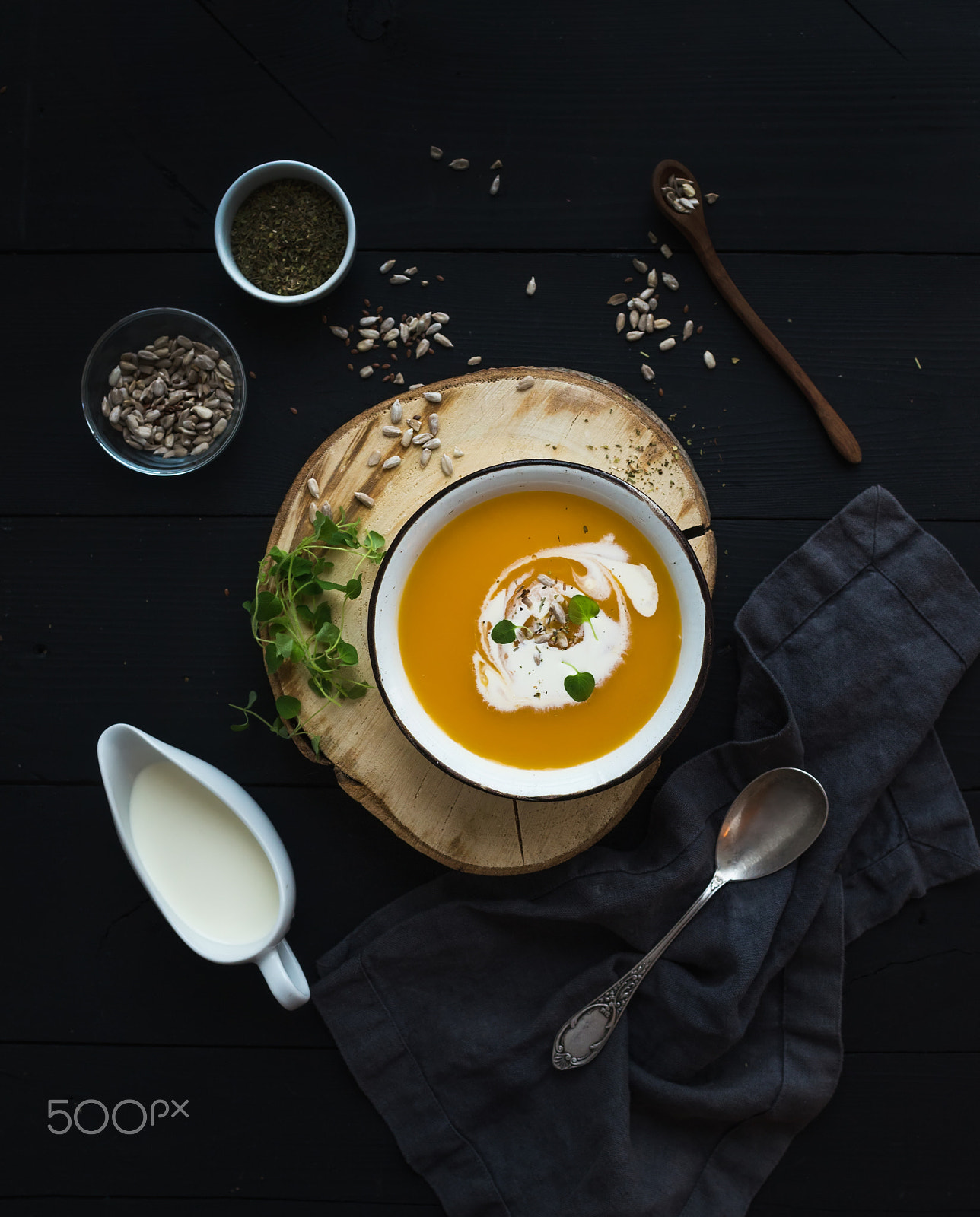 Nikon D610 + ZEISS Distagon T* 35mm F2 sample photo. Pumpkin soup with cream, seeds and spices in rustic metal bowl over grunge black background. top vie photography