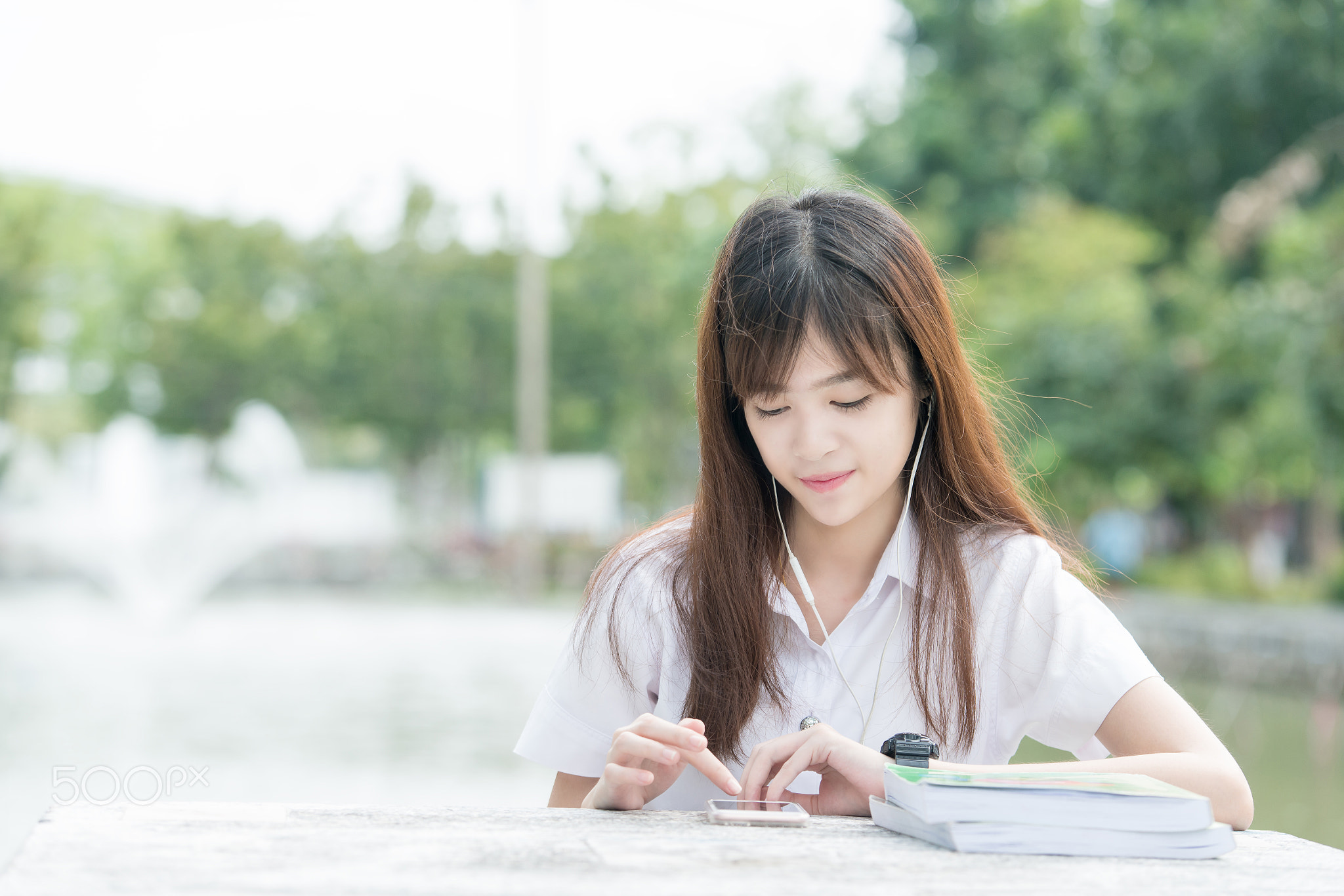 Asian student with uniform using smartphone