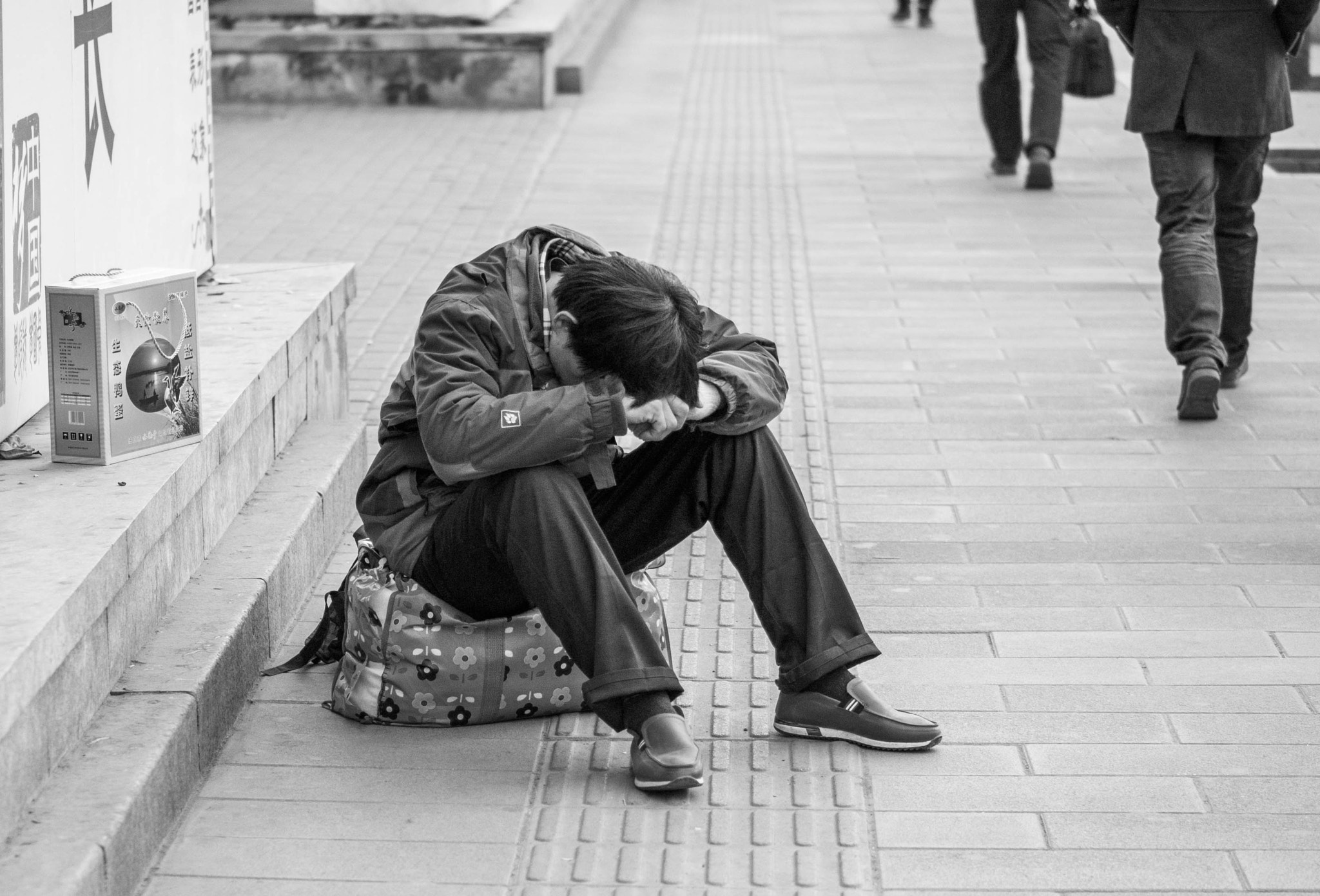 Panasonic DMC-GM1S + Panasonic Lumix G 42.5mm F1.7 ASPH Power OIS sample photo. A guy sits down in a corner of street photography