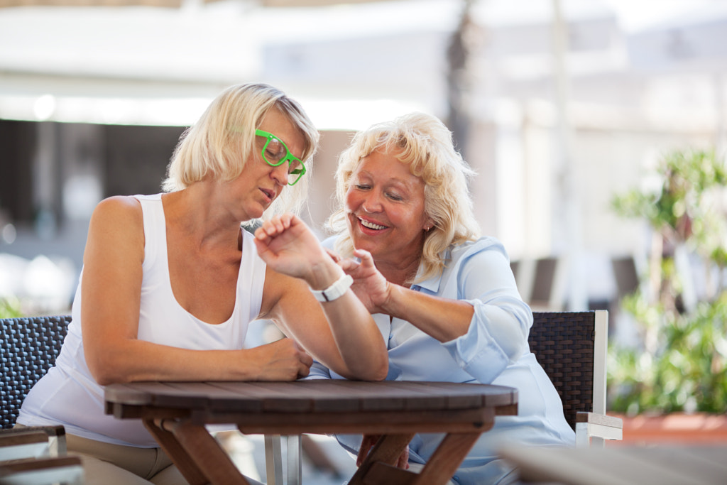 Mature women using smart watch in street cafe by Danil Roudenko on 500px.com