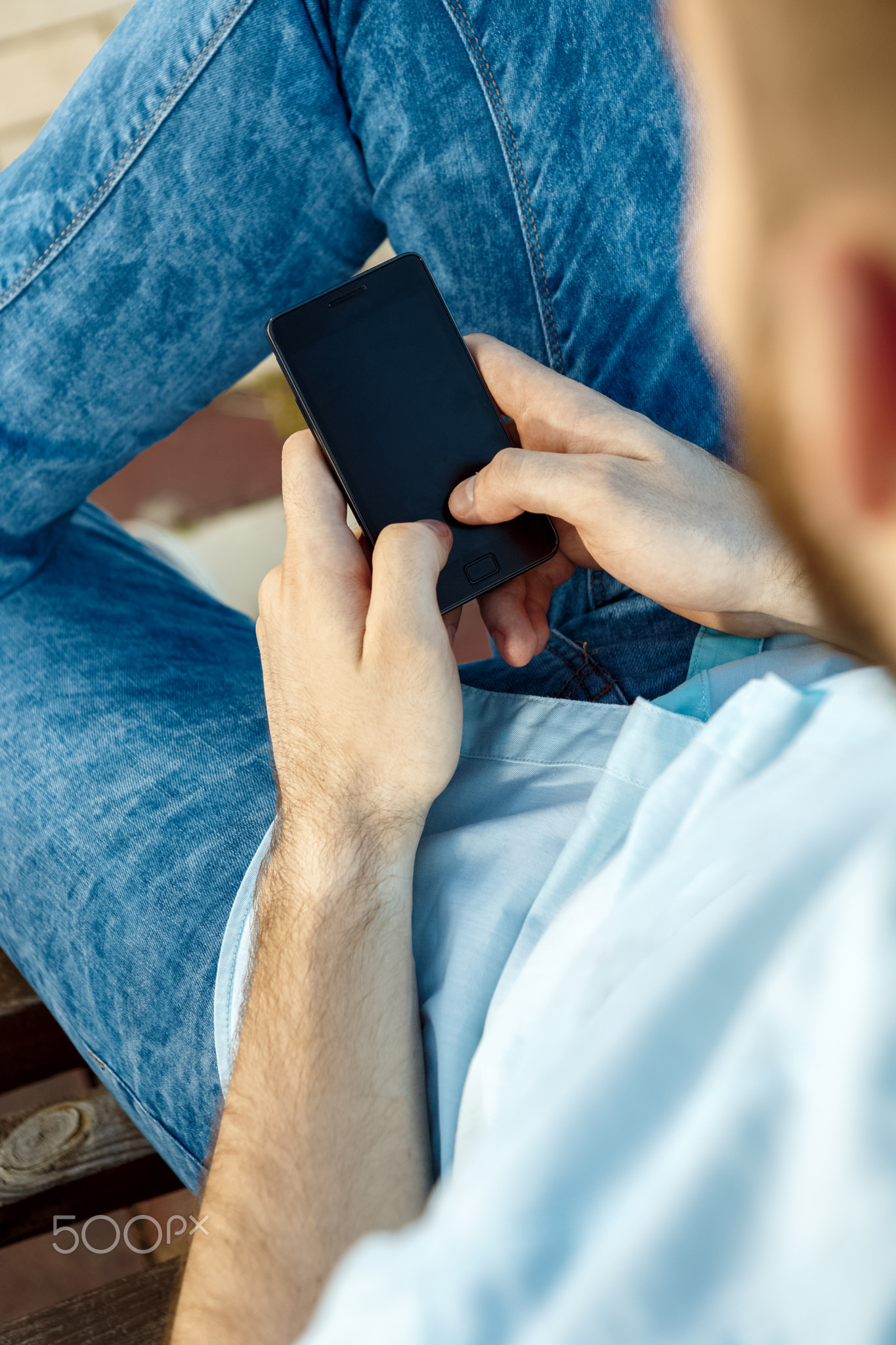 Smiling young man texting on the cellphone