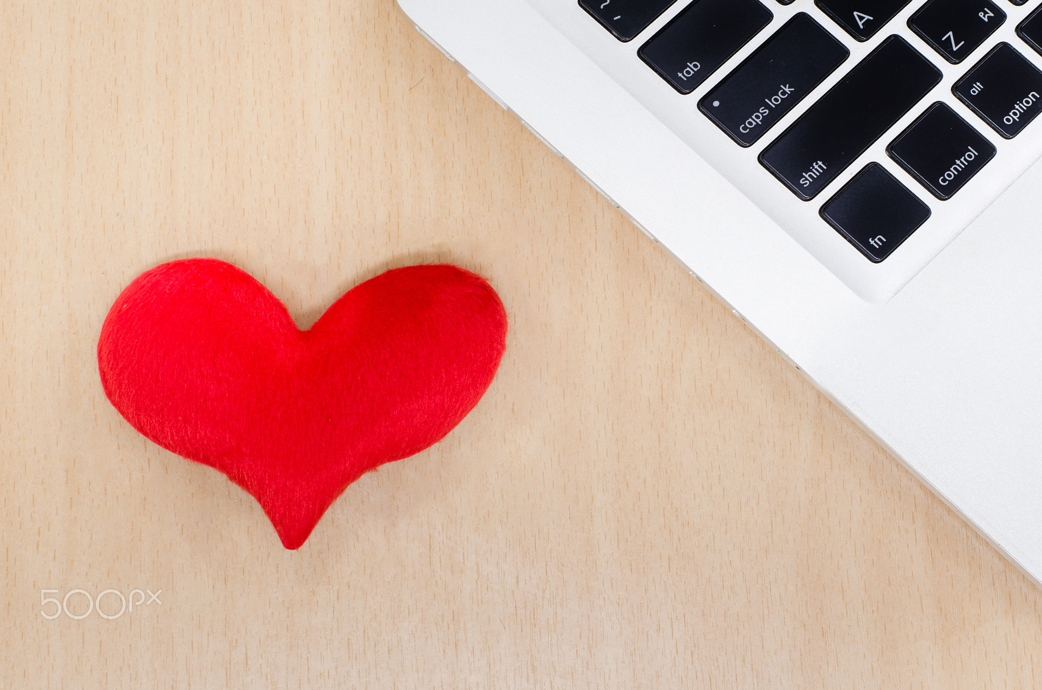 Red heart with laptop on wooden table