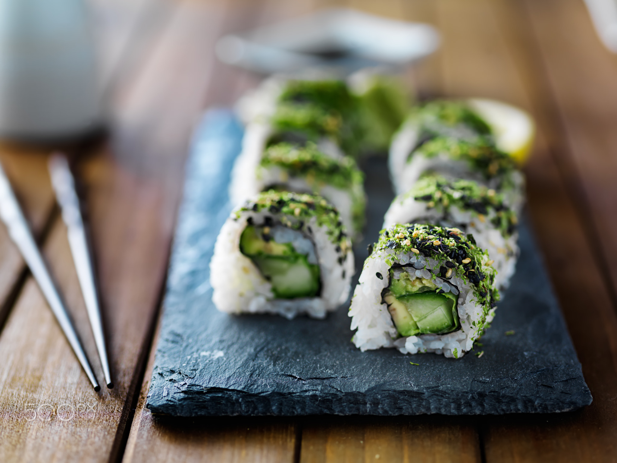 healthy kale, avocado and cucumber sushi roll on slate serving tray