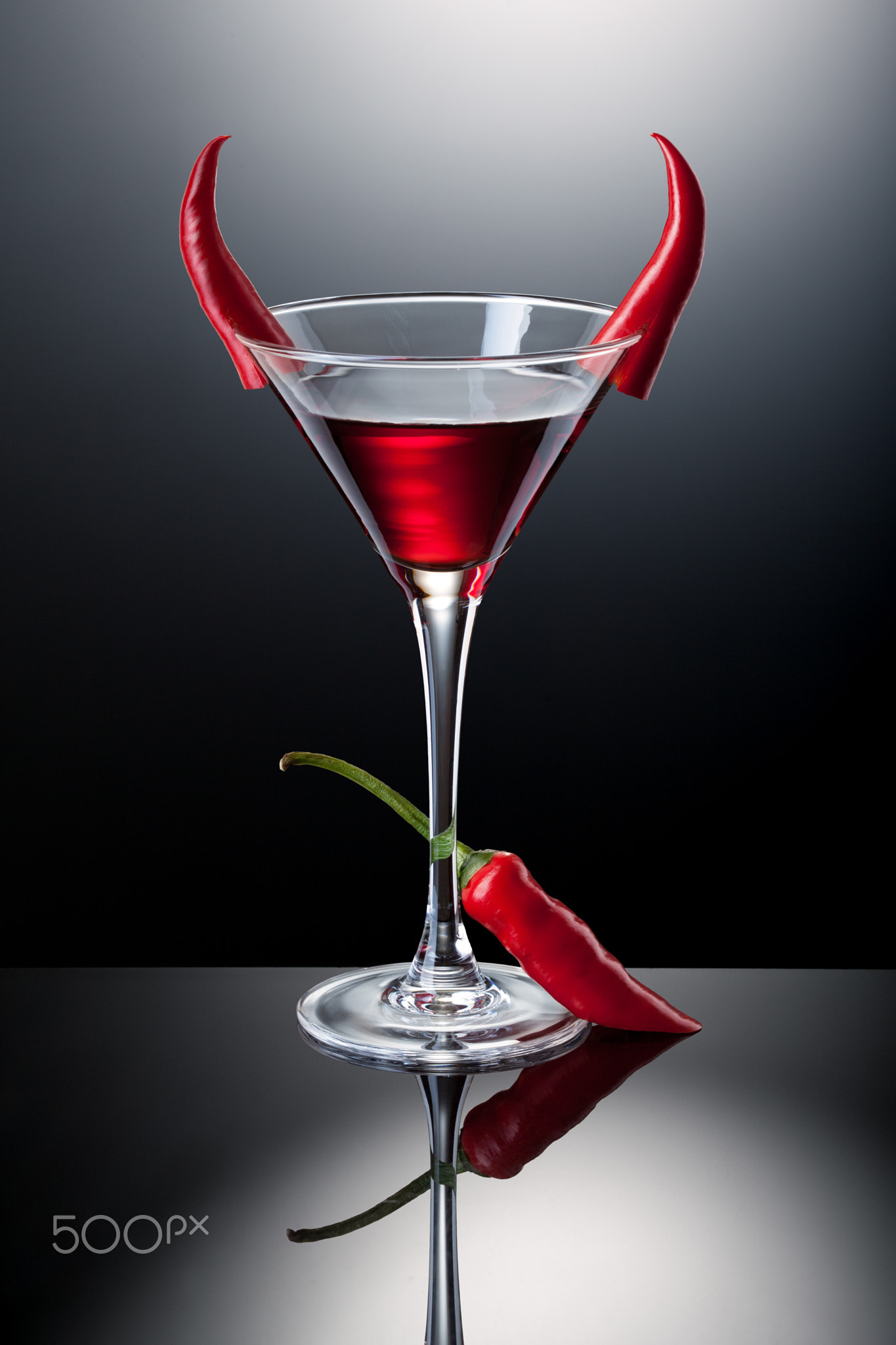 Glass of red martini decorated with chili pepper