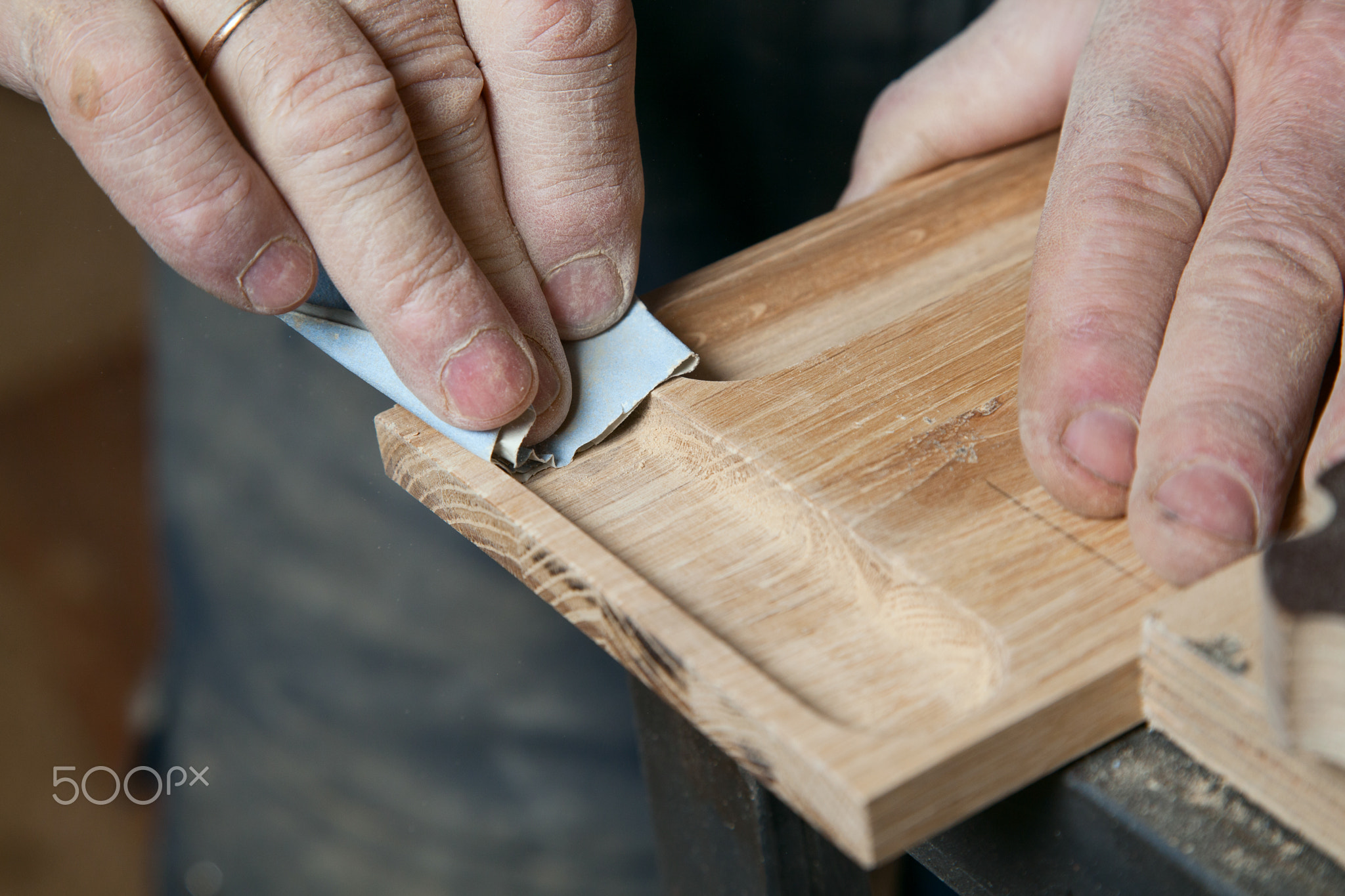 Men sandpaper grinds wood product in a workshop