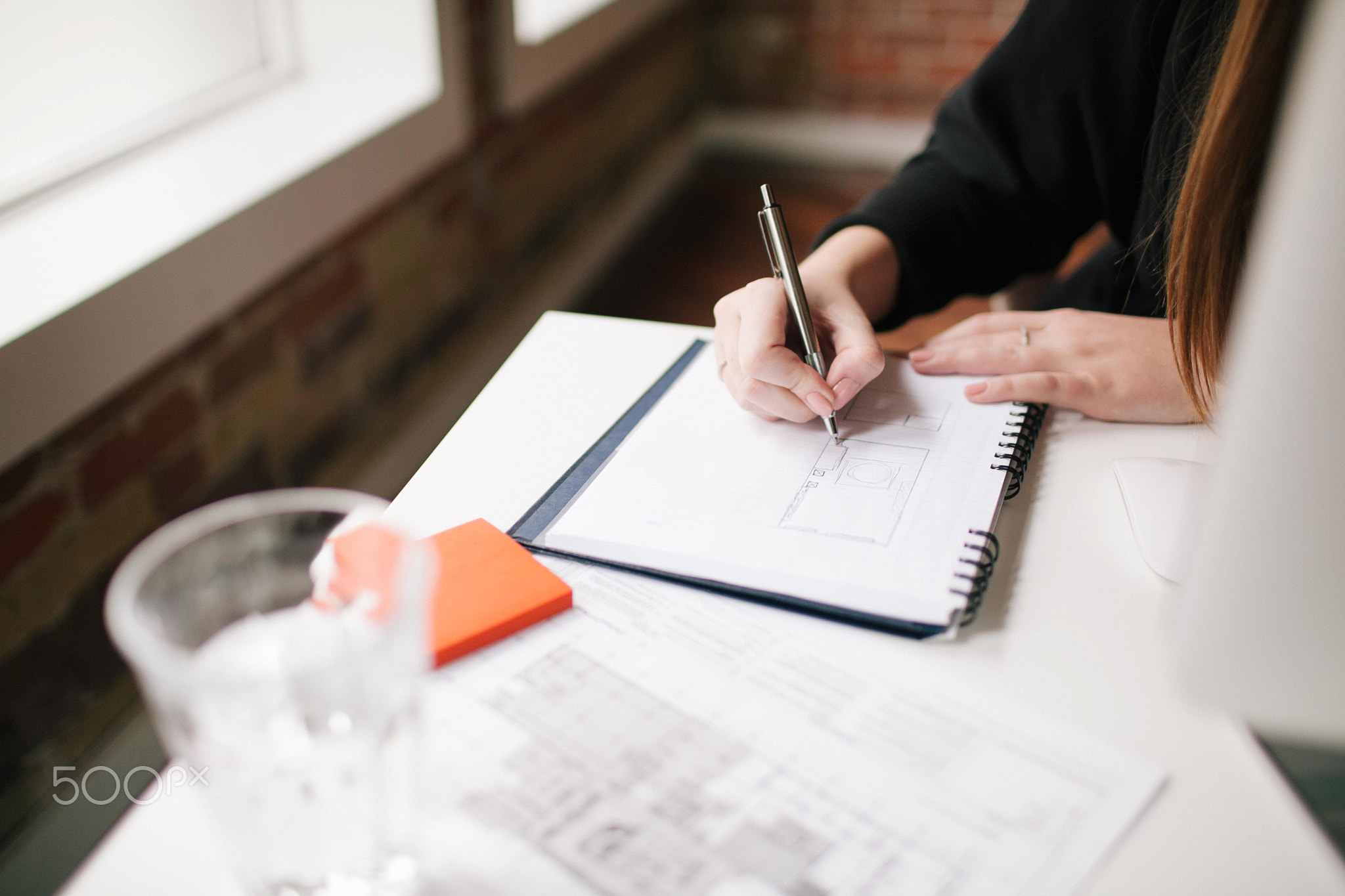 Businesswoman writing in notebook at desk.