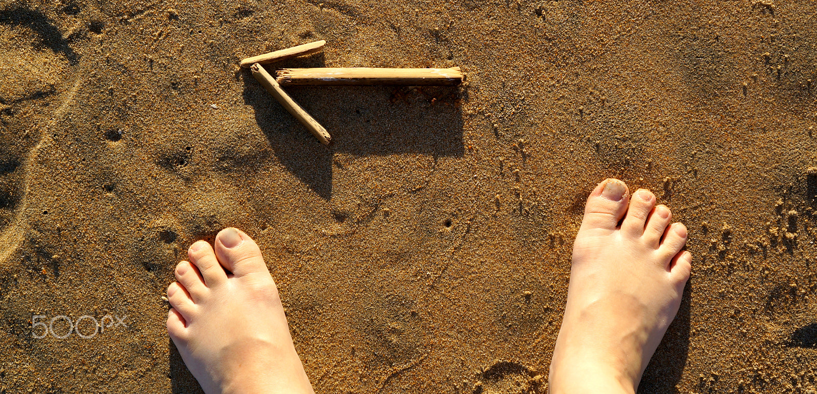 Sony E 18-55mm F3.5-5.6 OSS sample photo. Feet around stick arrow at the beach photography