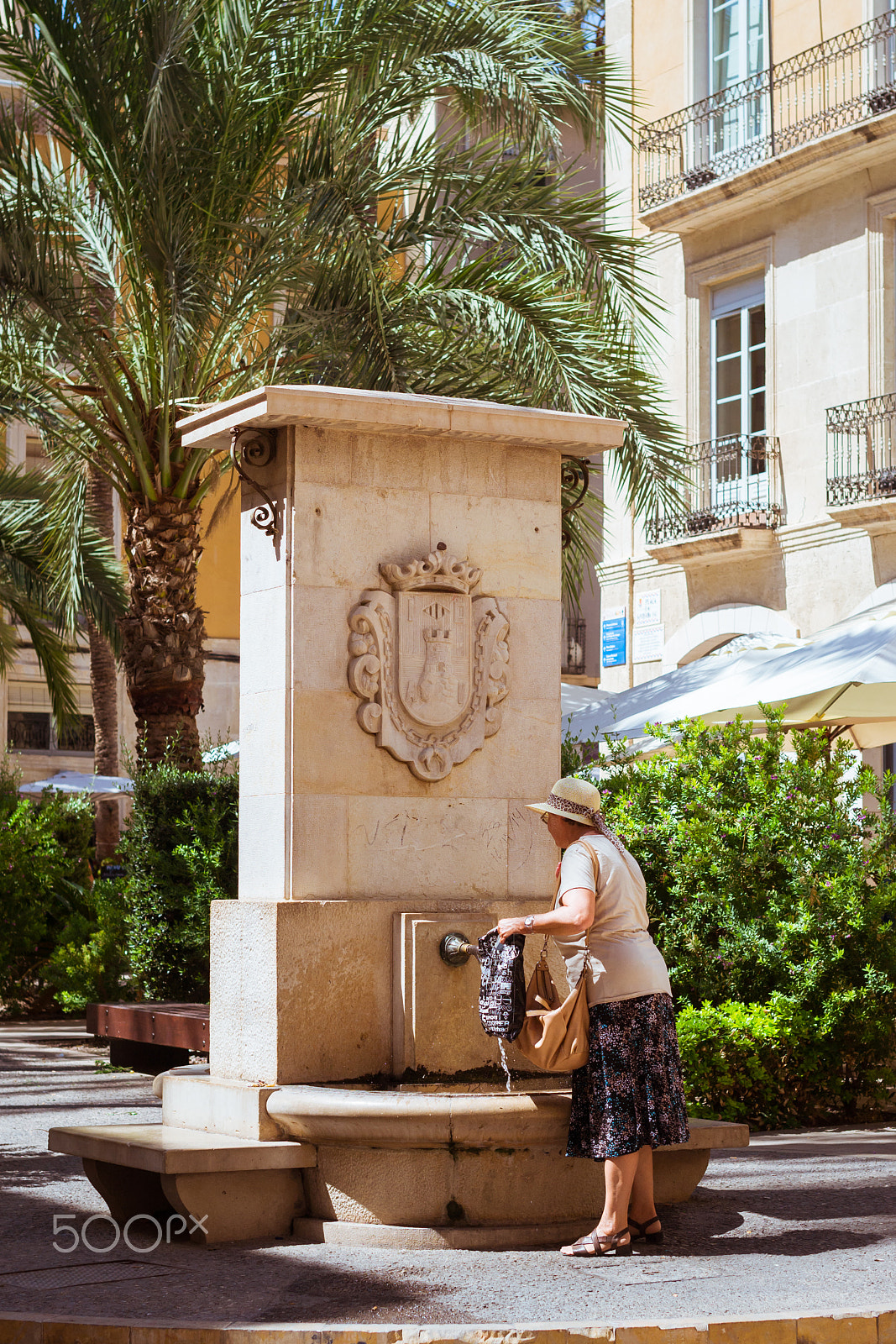 Nikon D3100 + Sigma 50mm F1.4 EX DG HSM sample photo. Elderly woman collects water in fountain on popular tourist stre photography