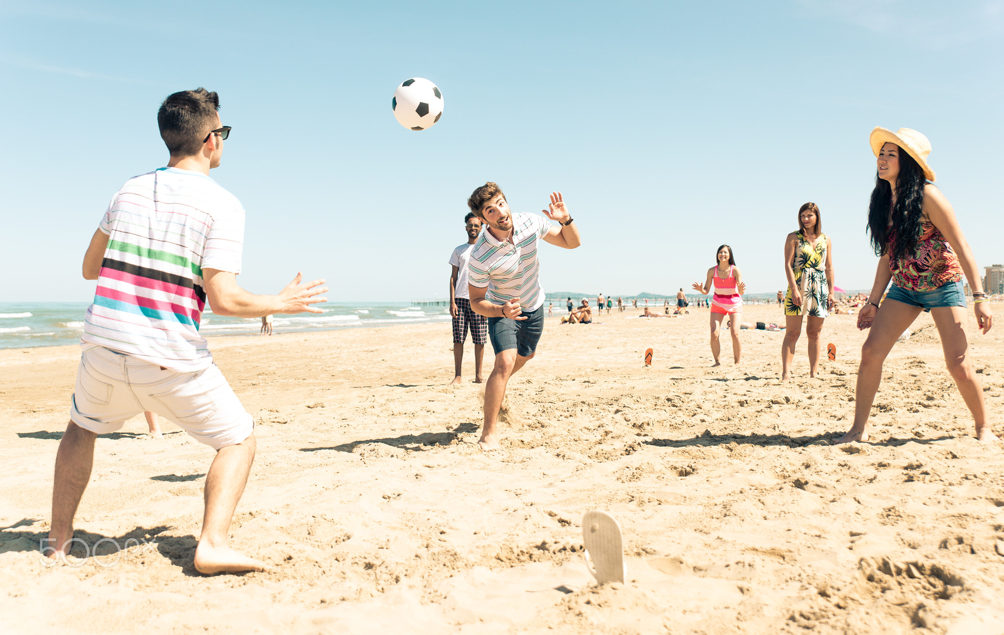 Group of friends having fun on the beach playing soccer
