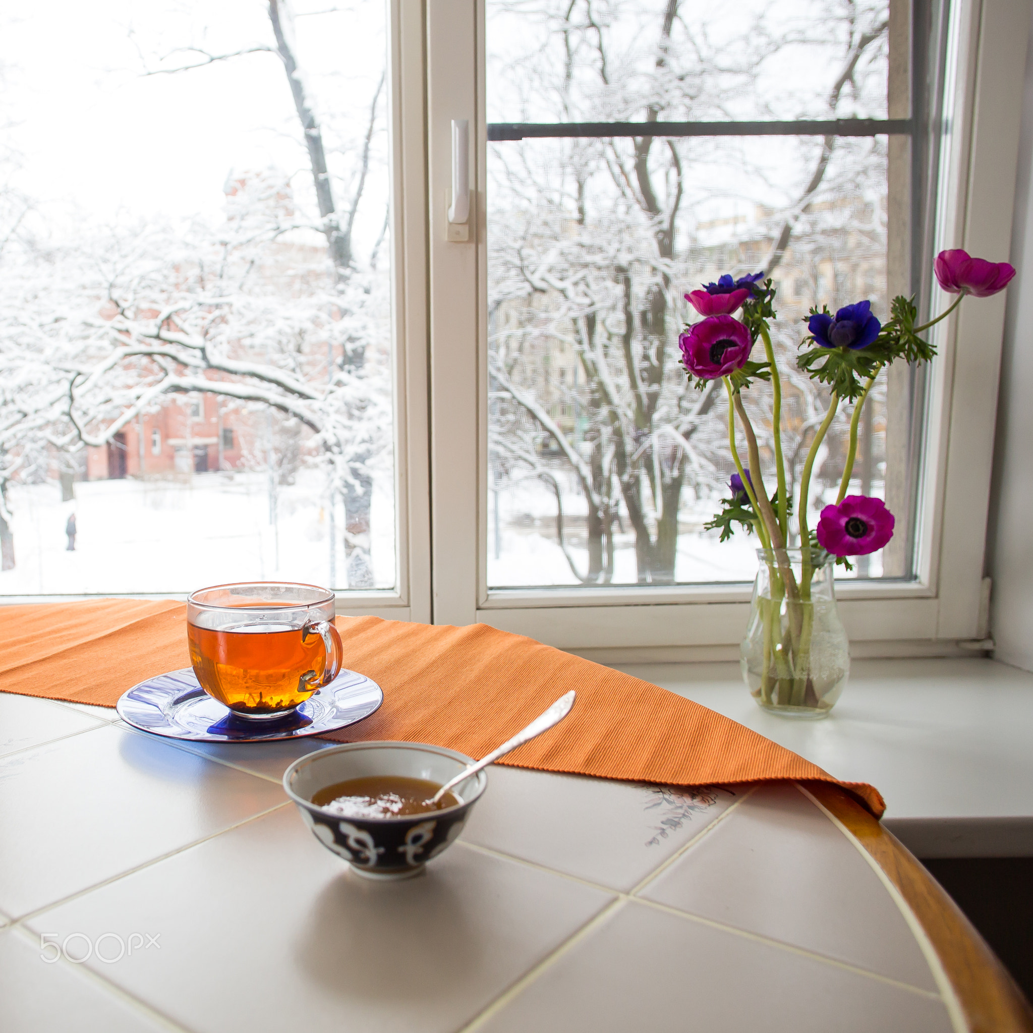 Winter breakfast scene: cup of tea, plate with orange jam