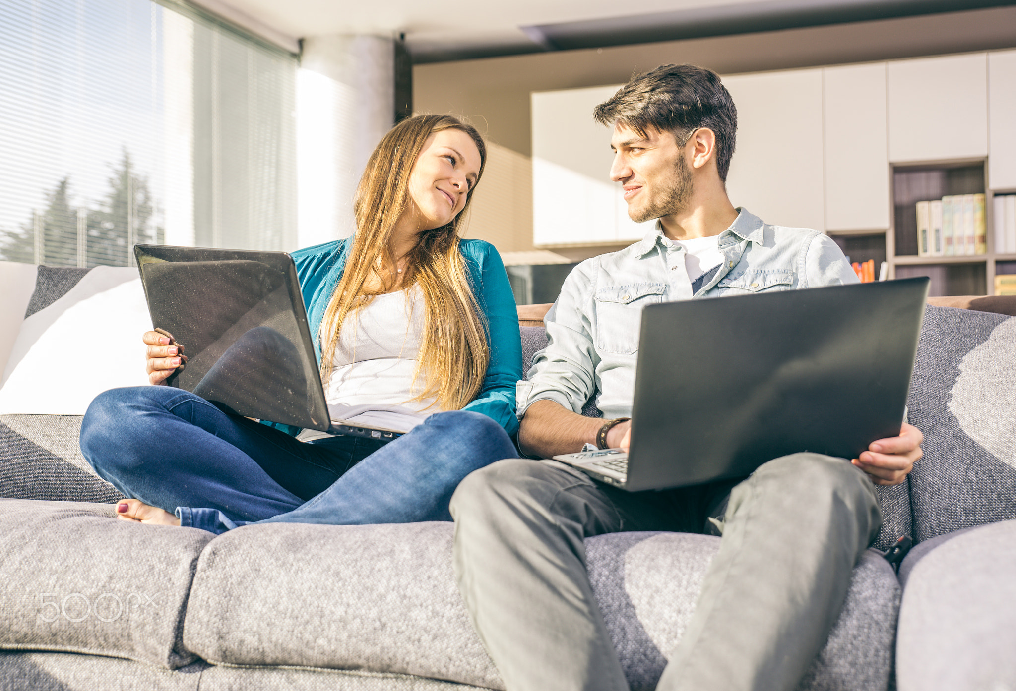 Happy couple watching things on computer, at home in the living