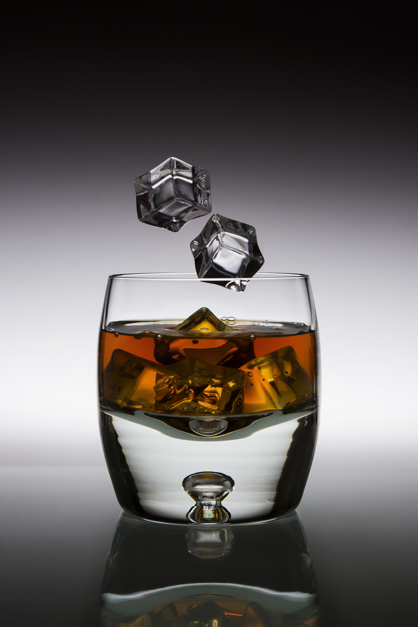 Nikon AF-S Nikkor 28-70mm F2.8 ED-IF sample photo. Amber alcoholic drink with falling ice in a glass photography