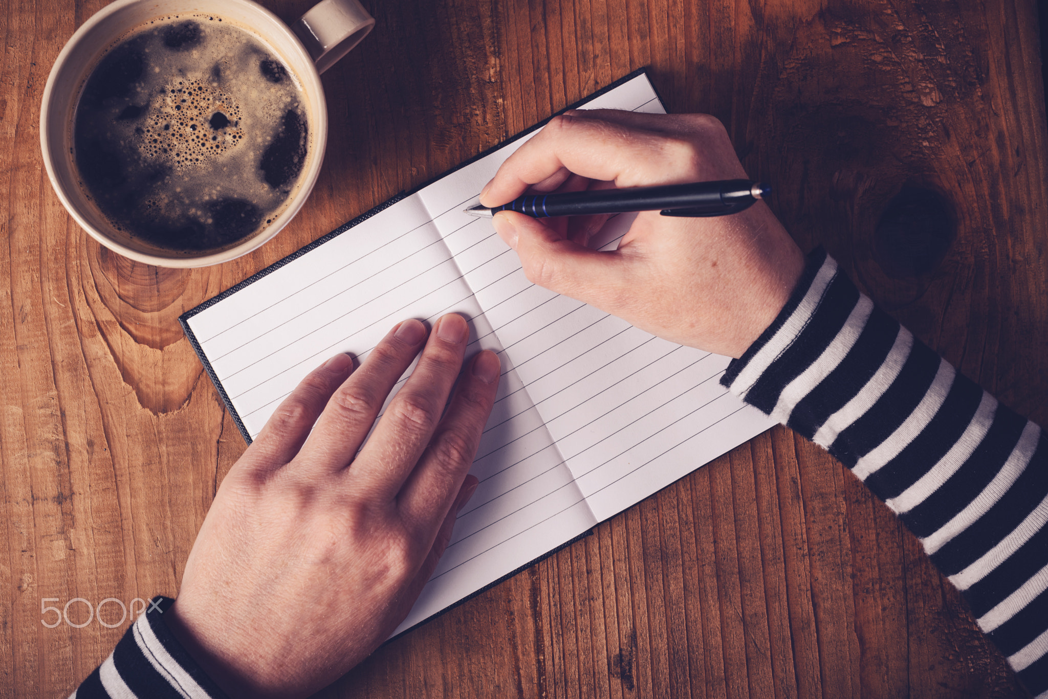 Woman drinking coffee and writing a diary note