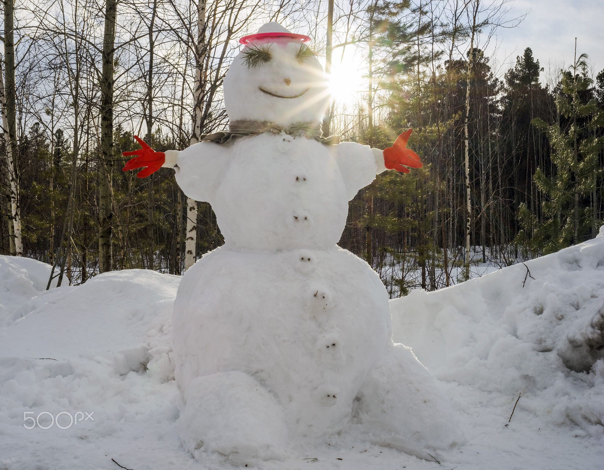 The snowman stands alone in the sunlight.