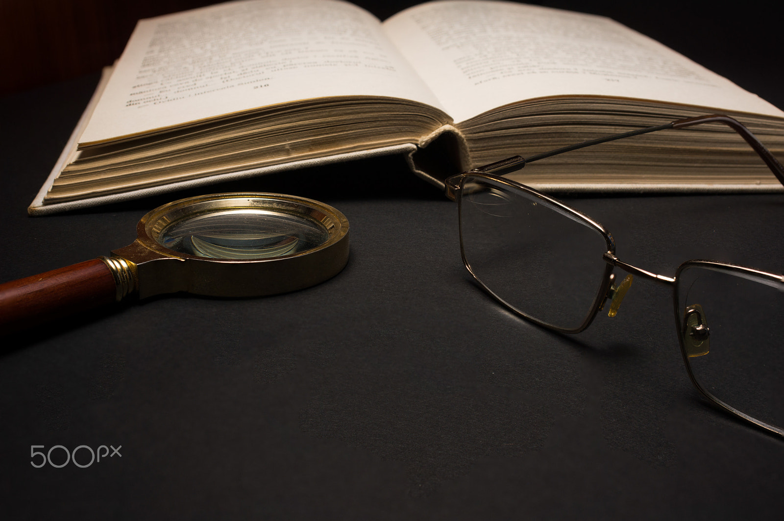 Sony SLT-A77 + Minolta AF 28-85mm F3.5-4.5 sample photo. Eyeglasses with magnifying glass on dark surface with books. photography