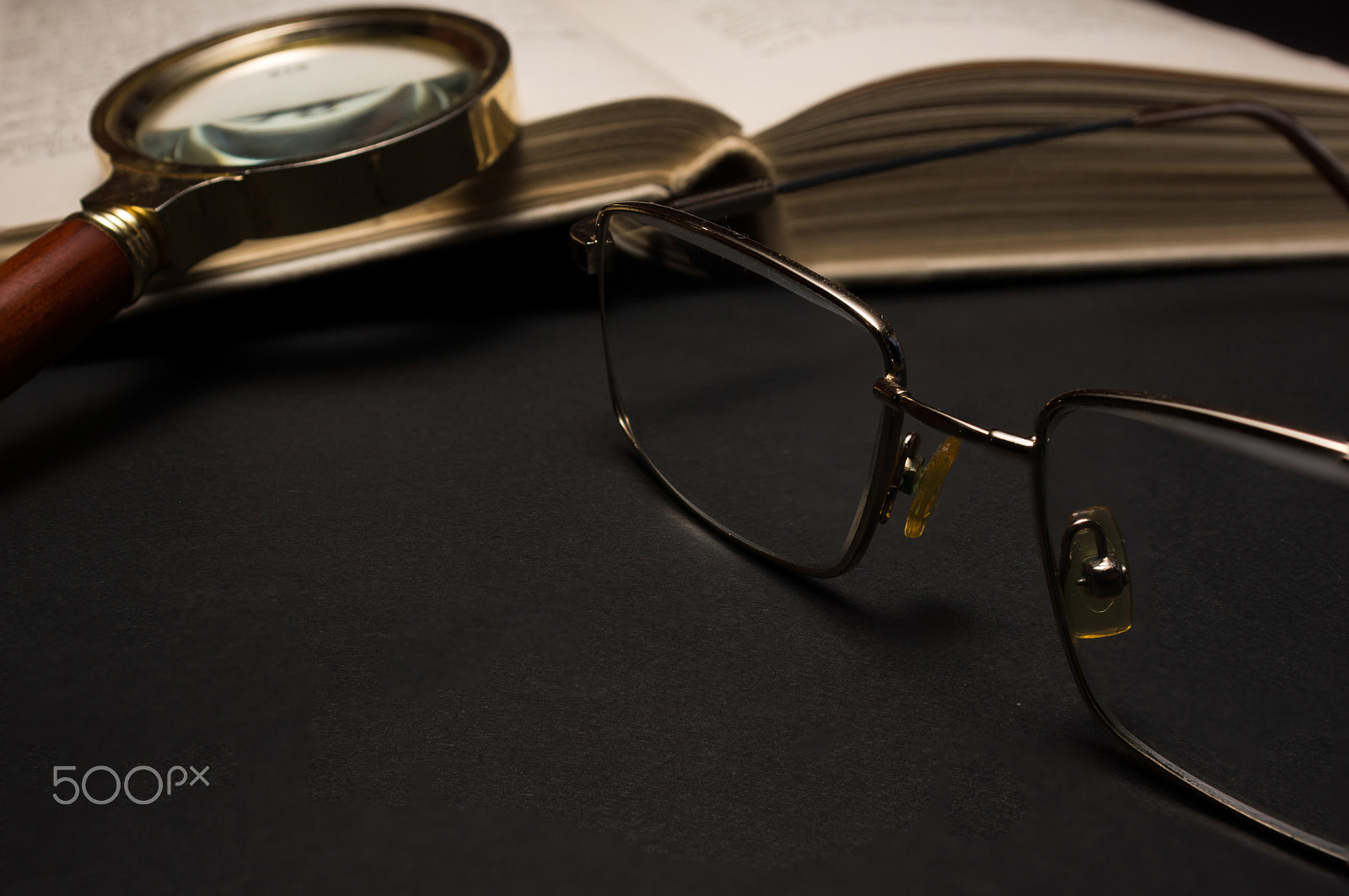 Sony SLT-A77 + Minolta AF 28-85mm F3.5-4.5 sample photo. Eyeglasses with magnifying glass on dark surface with books. photography