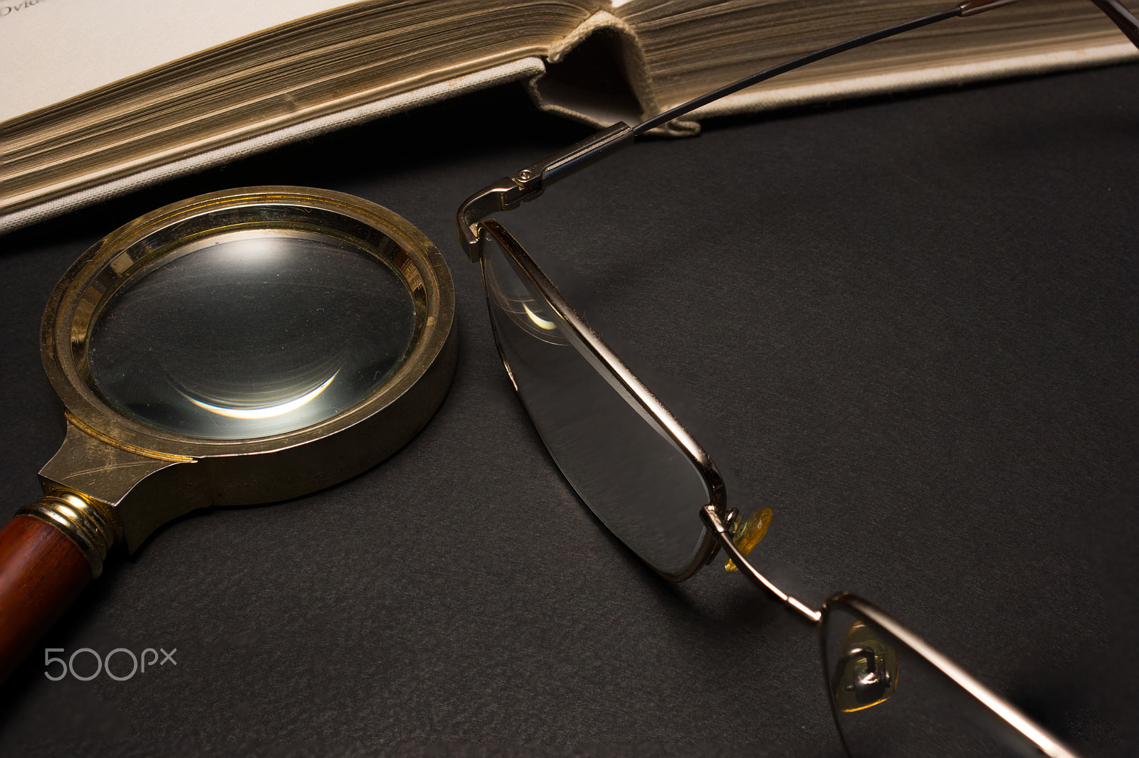 Sony SLT-A77 + Minolta AF 28-85mm F3.5-4.5 sample photo. Eyeglasses with magnifying glass on dark surface with books. photography