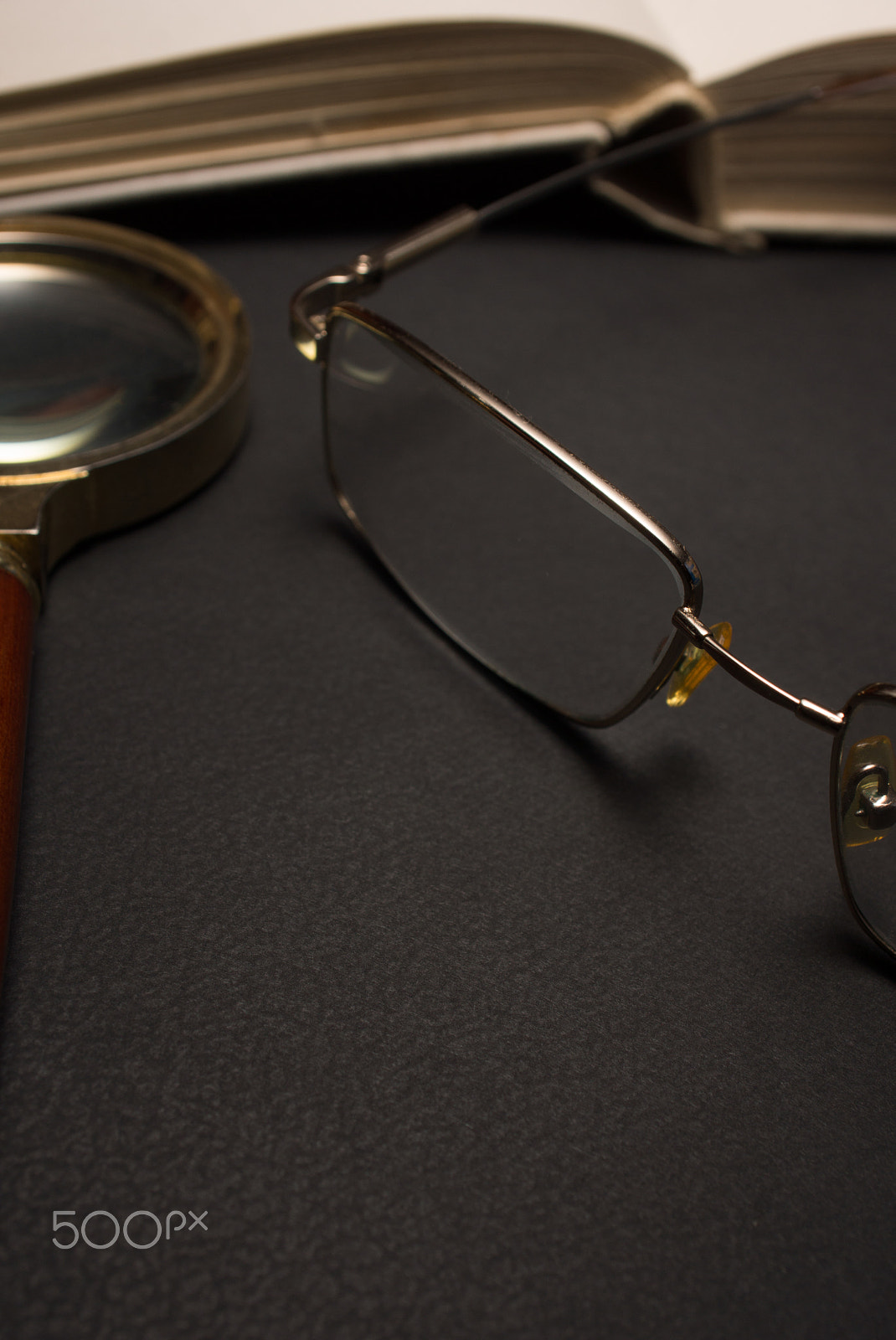 Sony SLT-A77 + Minolta AF 28-85mm F3.5-4.5 sample photo. Eyeglasses with magnifying glass on dark surface with books. photography