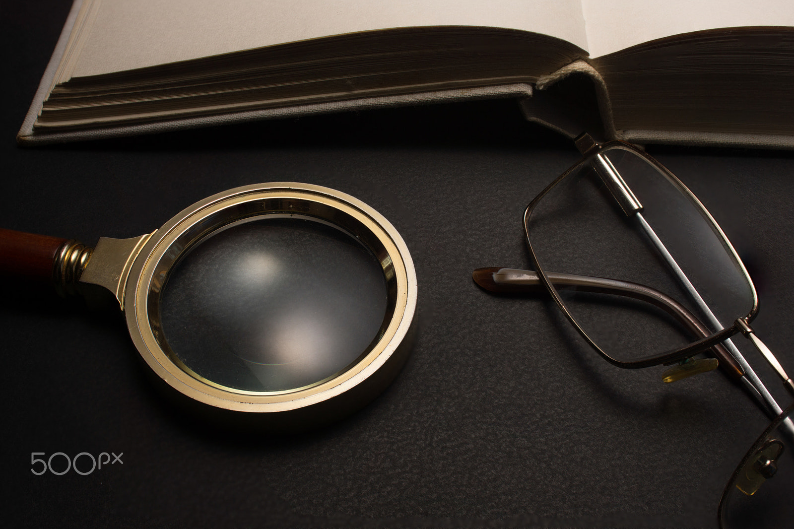 Sony SLT-A77 + Minolta AF 28-85mm F3.5-4.5 sample photo. Eyeglasses with magnifying glass on dark surface with books. photography