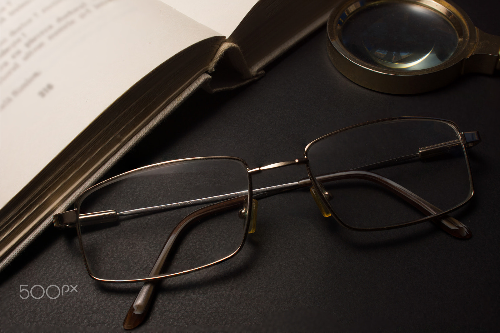 Sony SLT-A77 + Minolta AF 28-85mm F3.5-4.5 sample photo. Eyeglasses with magnifying glass on dark surface with books. photography